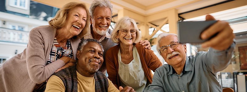 Group of diverse seniors taking a selfie together, smiling and enjoying each other's company.