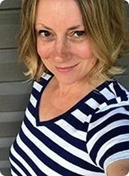 A woman with shoulder-length blonde hair, wearing a navy blue and white striped shirt, smiling at the camera.