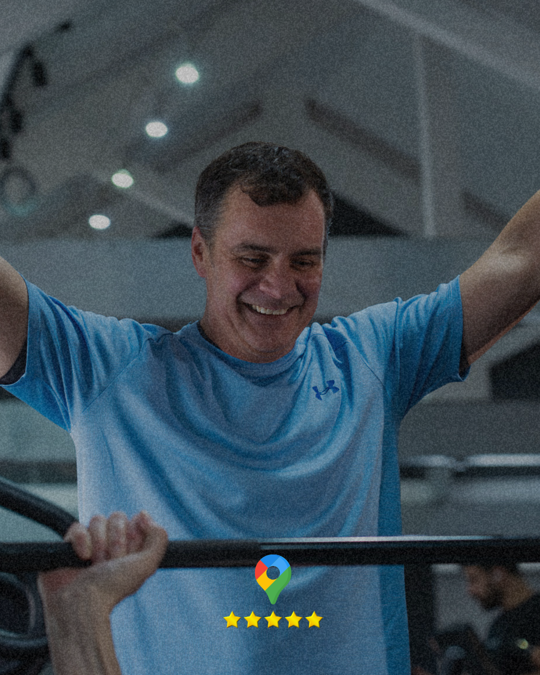 A middle-aged man, smiling in a gym in Stroud. Strength training whilst being personally trained.