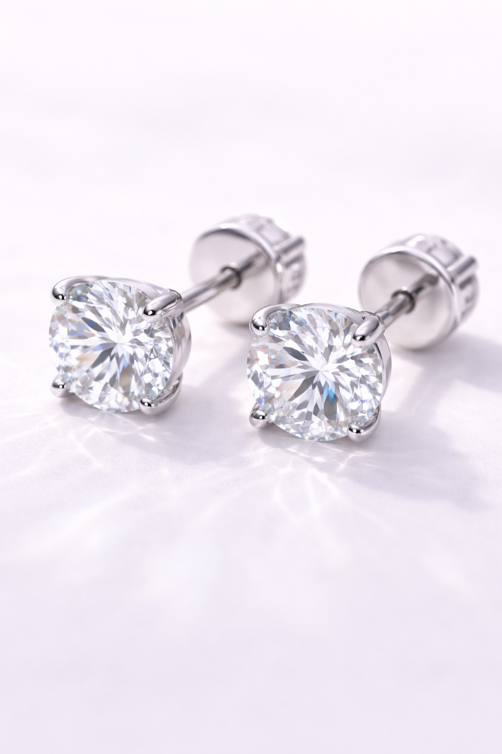 A pair of diamond stud earrings on a white surface.