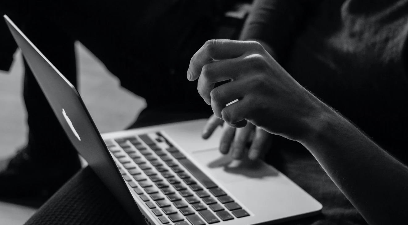 A person using a laptop, with one hand on the keyboard and the other hand near the trackpad.