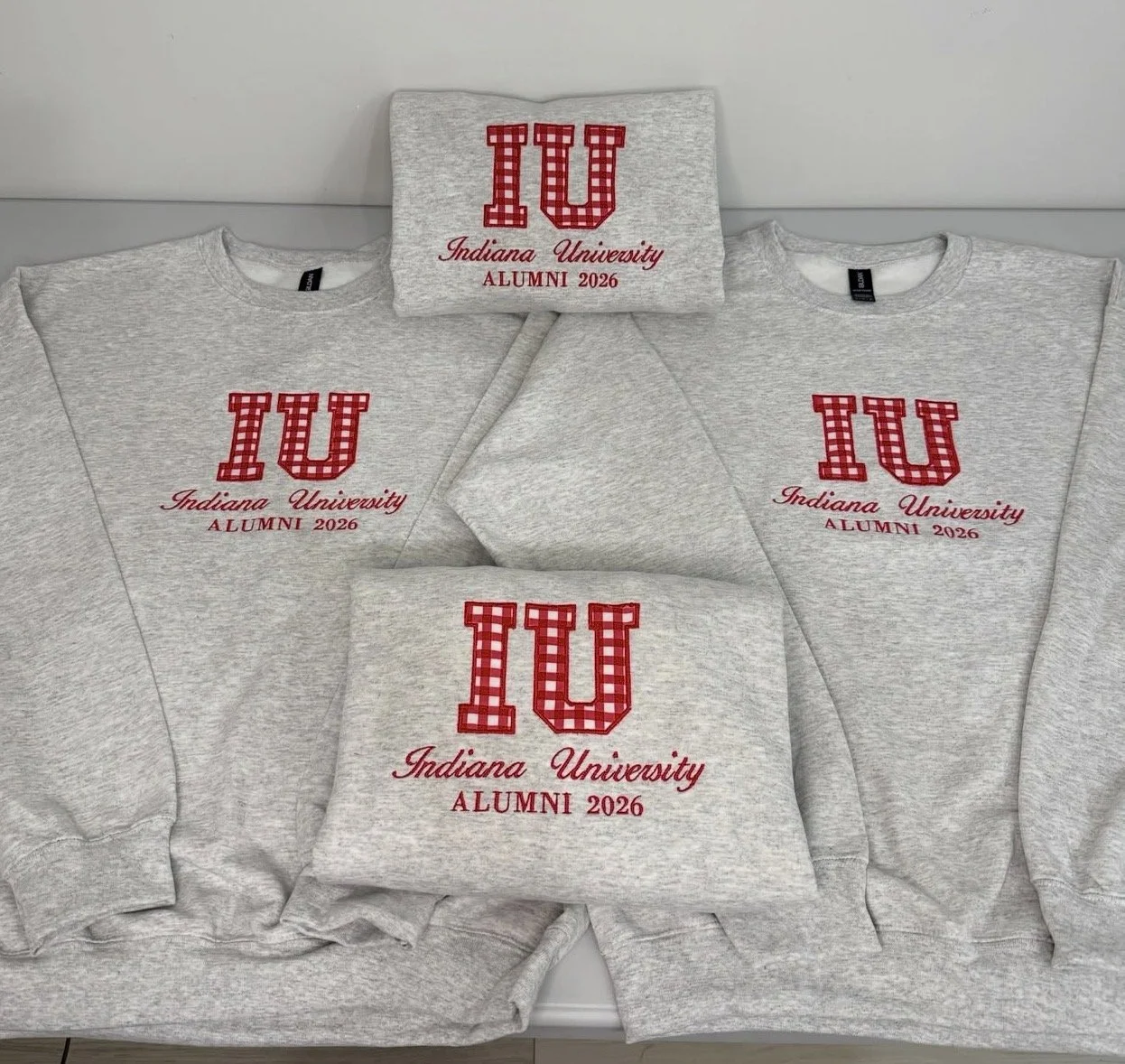 Gray sweatshirts and a gray towel with red and white checkered IU logo, Indiana University, ALUMNI 2026.