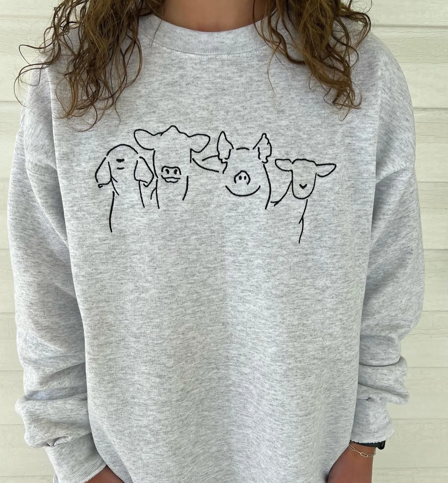 Gray sweatshirt with a line drawing of five cows on the chest.