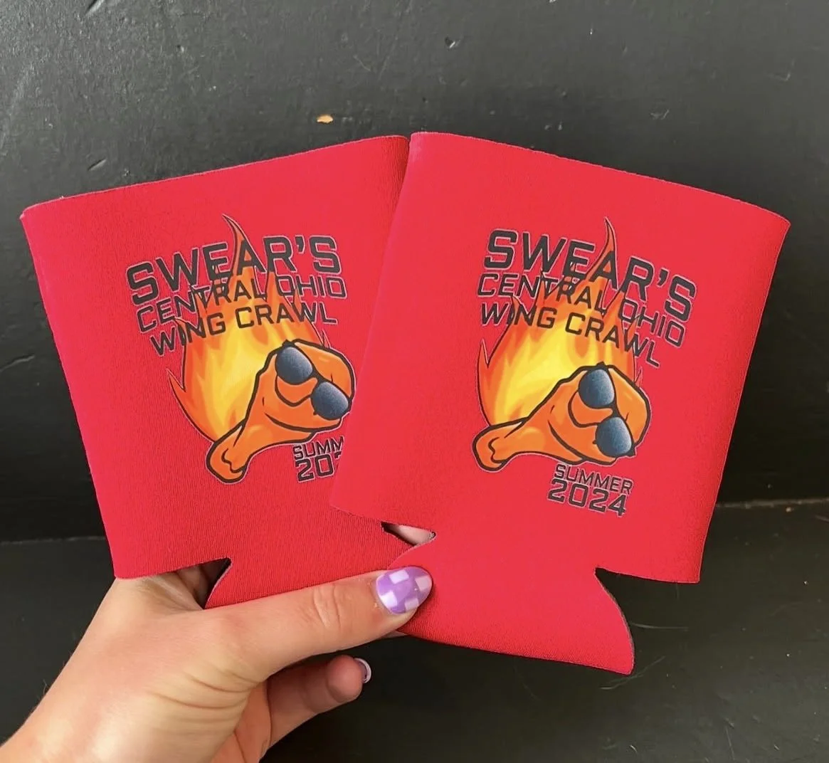 Two red sweatbands with a logo and text for Sweat Central Ohio Wing Crawl Summer 2024, featuring a pointing hand wearing sunglasses with a flame background.