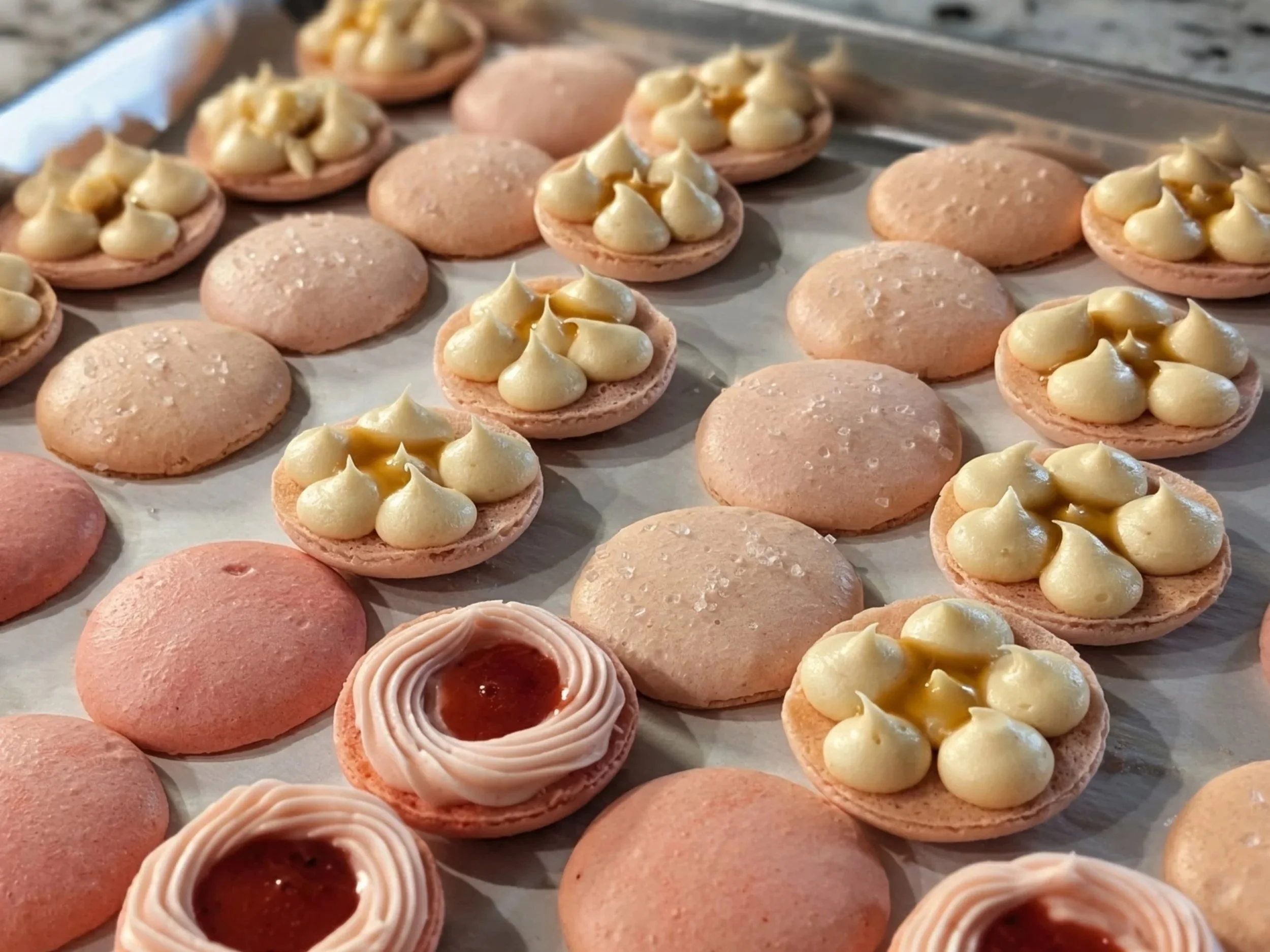 Assorted macarons in various colors and styles arranged on a tray.