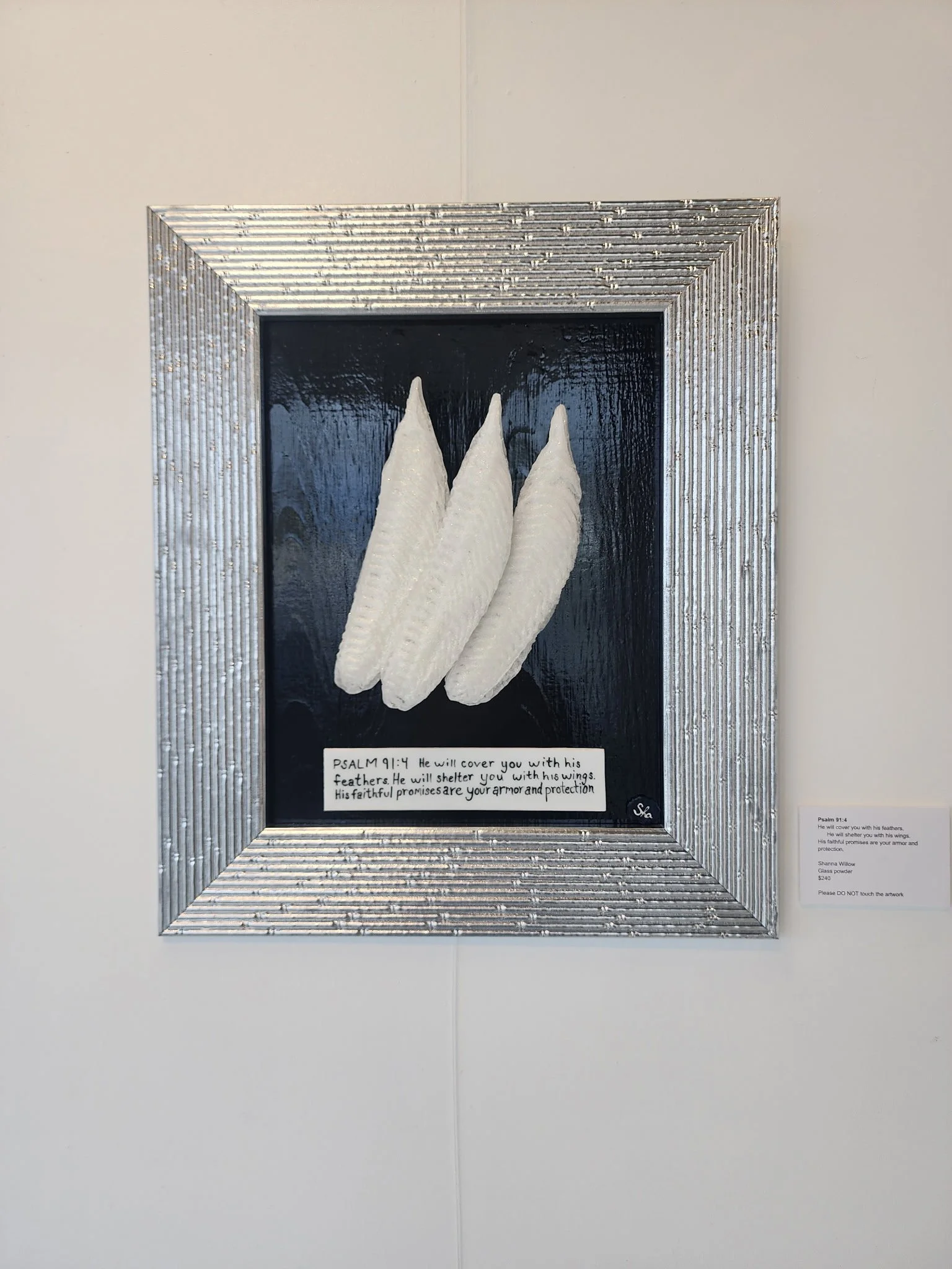 Art piece featuring three white corn cobs on a black background. Includes a quote from Psalm 91:4 about God's protection and a small note indicating the title, artist, and price.