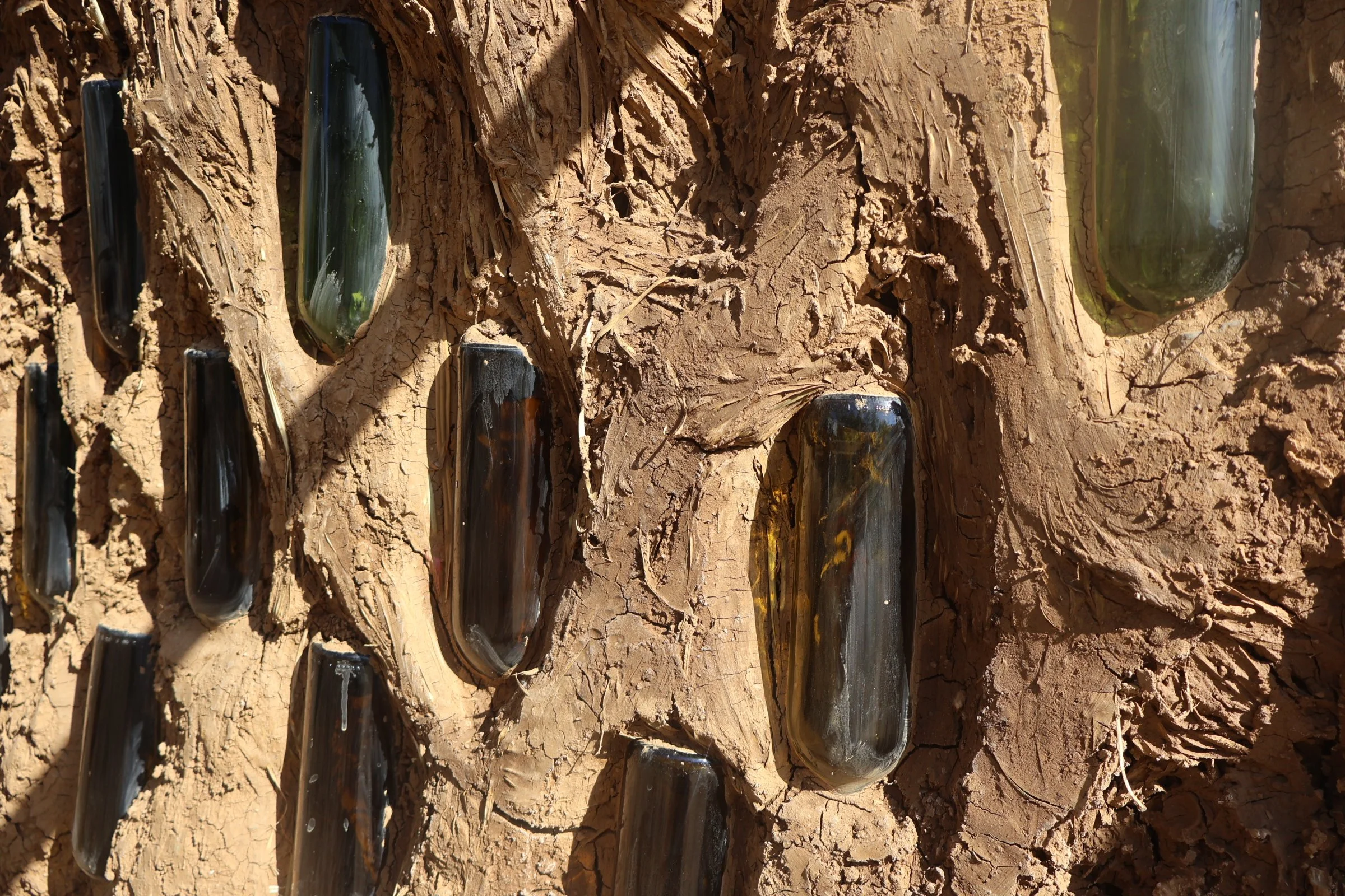 Vasos de vidrio enterrados en tierra agrietada, parcialmente cubiertos de barro.