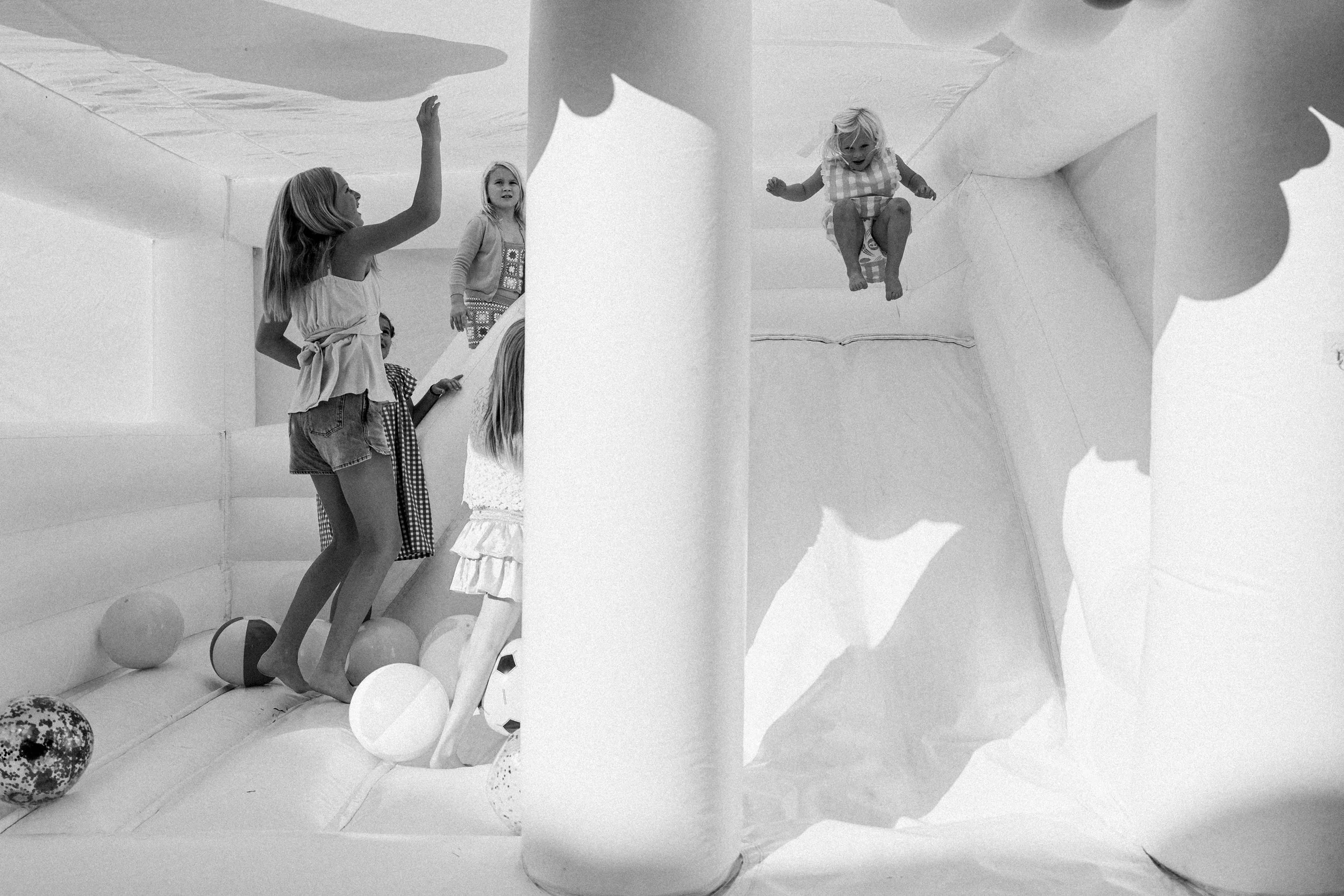 Mountain Brook, AL - Children playing and jumping inside an inflatable bounce house with a central support pole, some children are partially visible, and the bounce house has padded walls and floor with balls scattered inside.