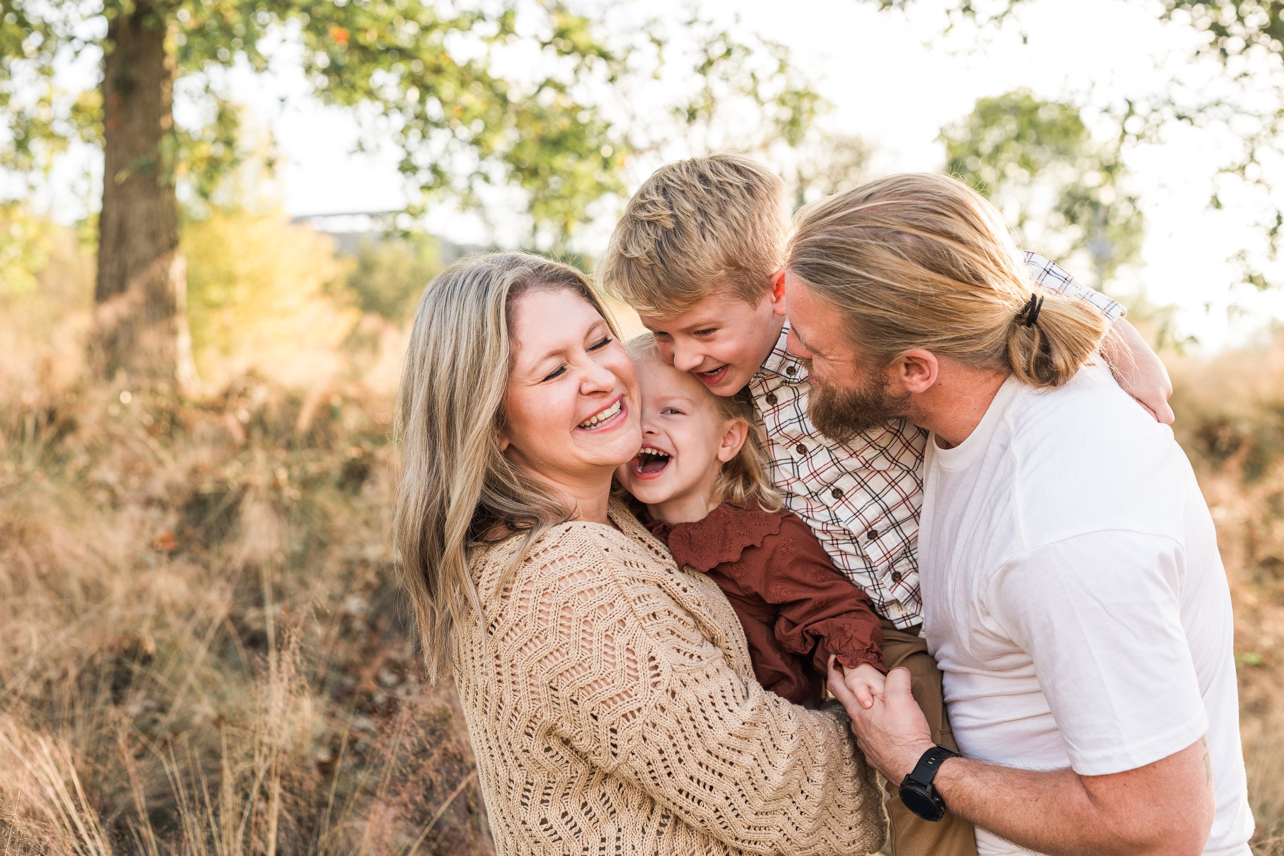 Railroad Park, Downtown Birmingham, AL - A happy family outdoors in a park, smiling and laughing as they hug and play together.