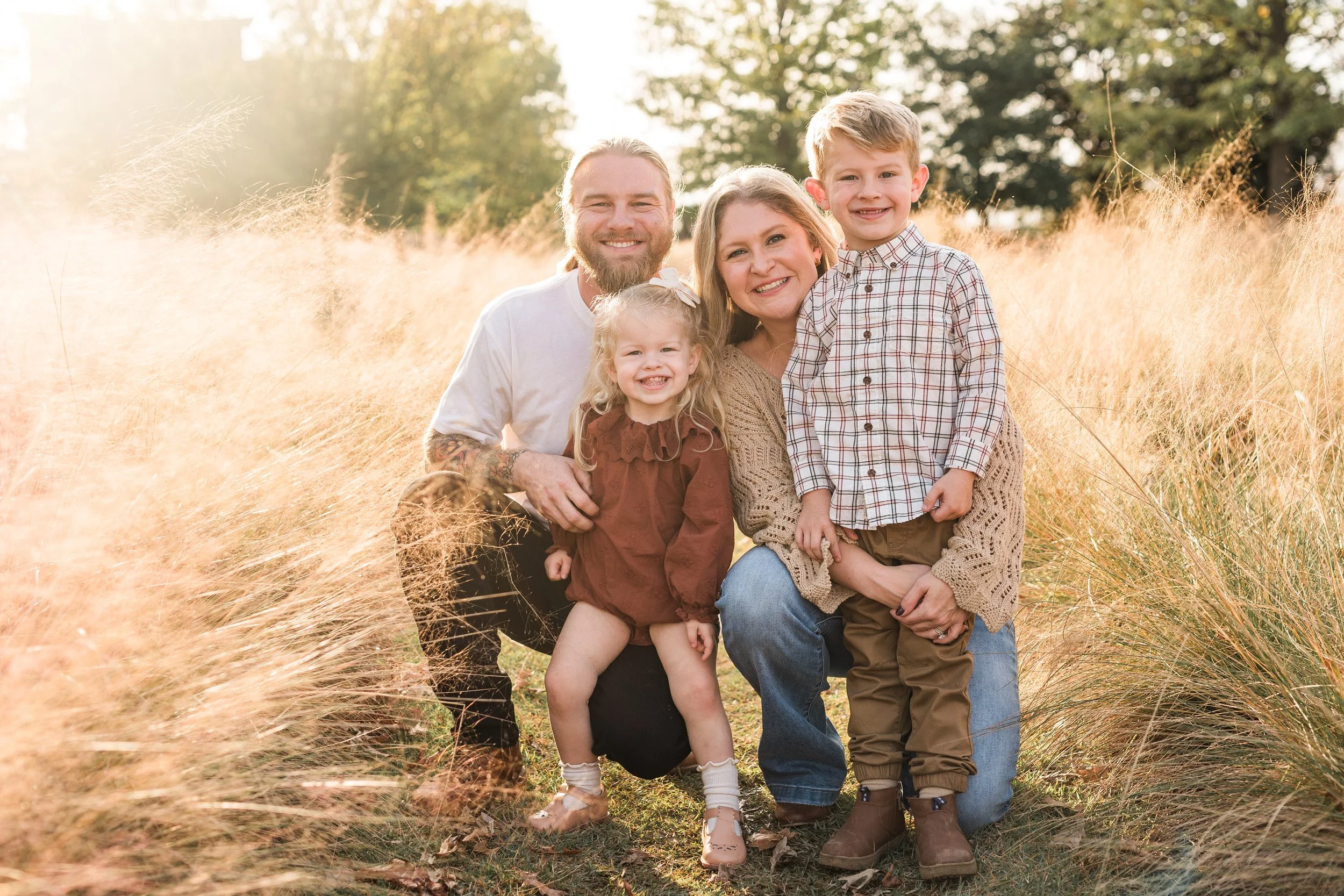 Railroad Park, Downtown Birmingham, AL - A happy family of four outdoors in a field of tall golden grass during late afternoon, smiling at the camera.
