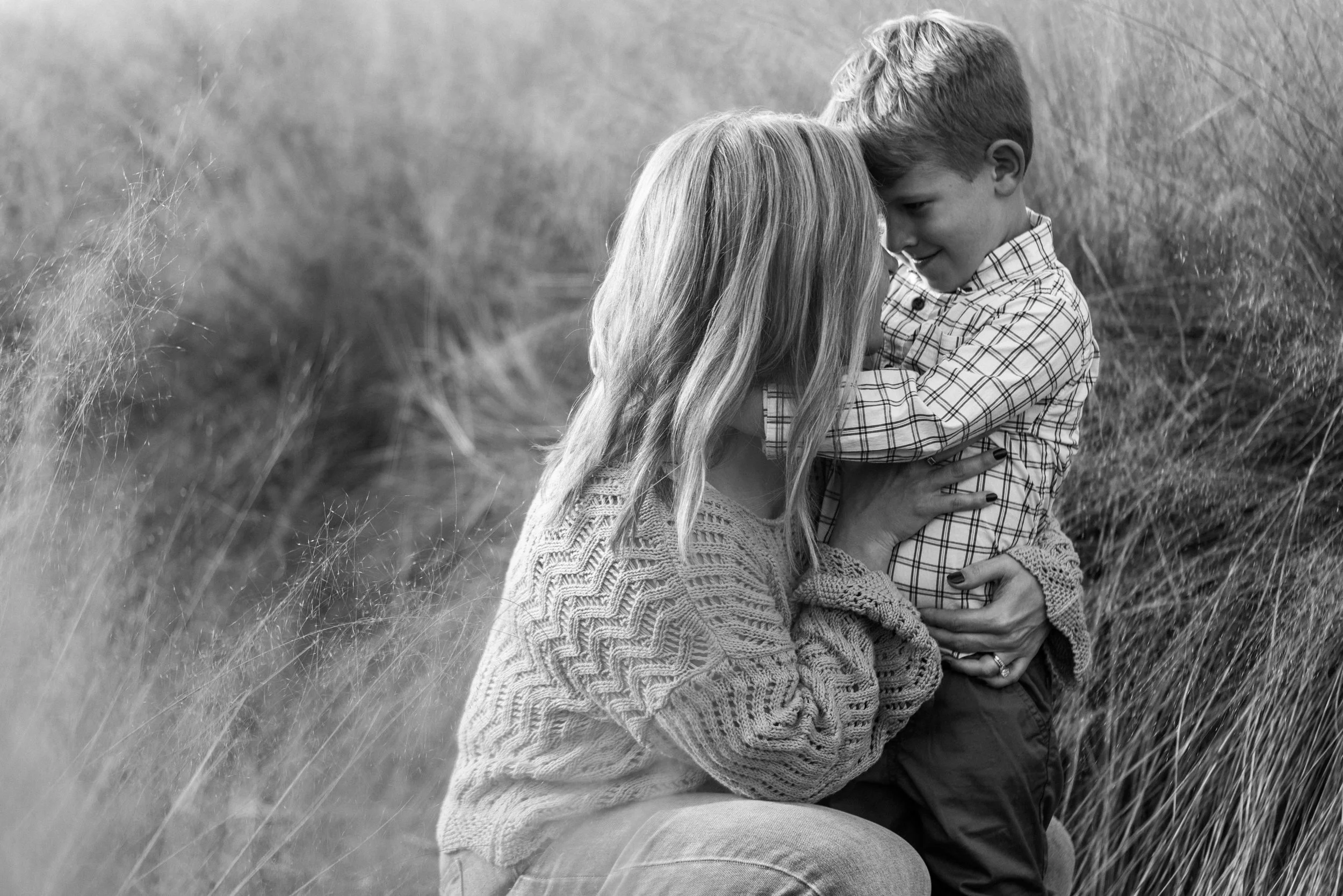 Railroad Park, Downtown Birmingham, AL - A woman and a young boy sharing a tender moment outdoors in a grassy field, with the woman holding the boy close as they touch foreheads.