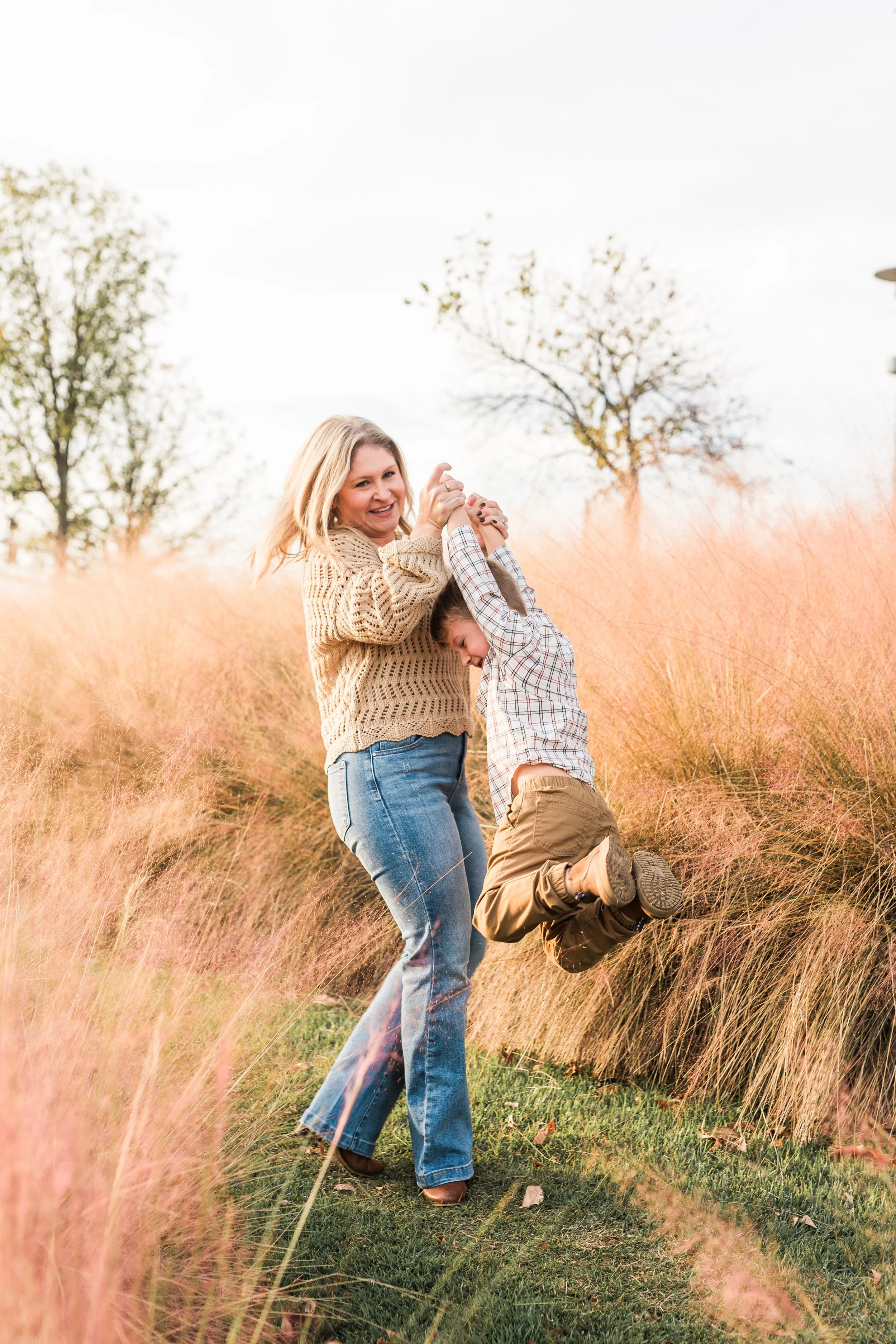 Railroad Park, Downtown Birmingham, AL - A woman and a young boy playing and smiling outdoors in a field of pink grass during daytime.