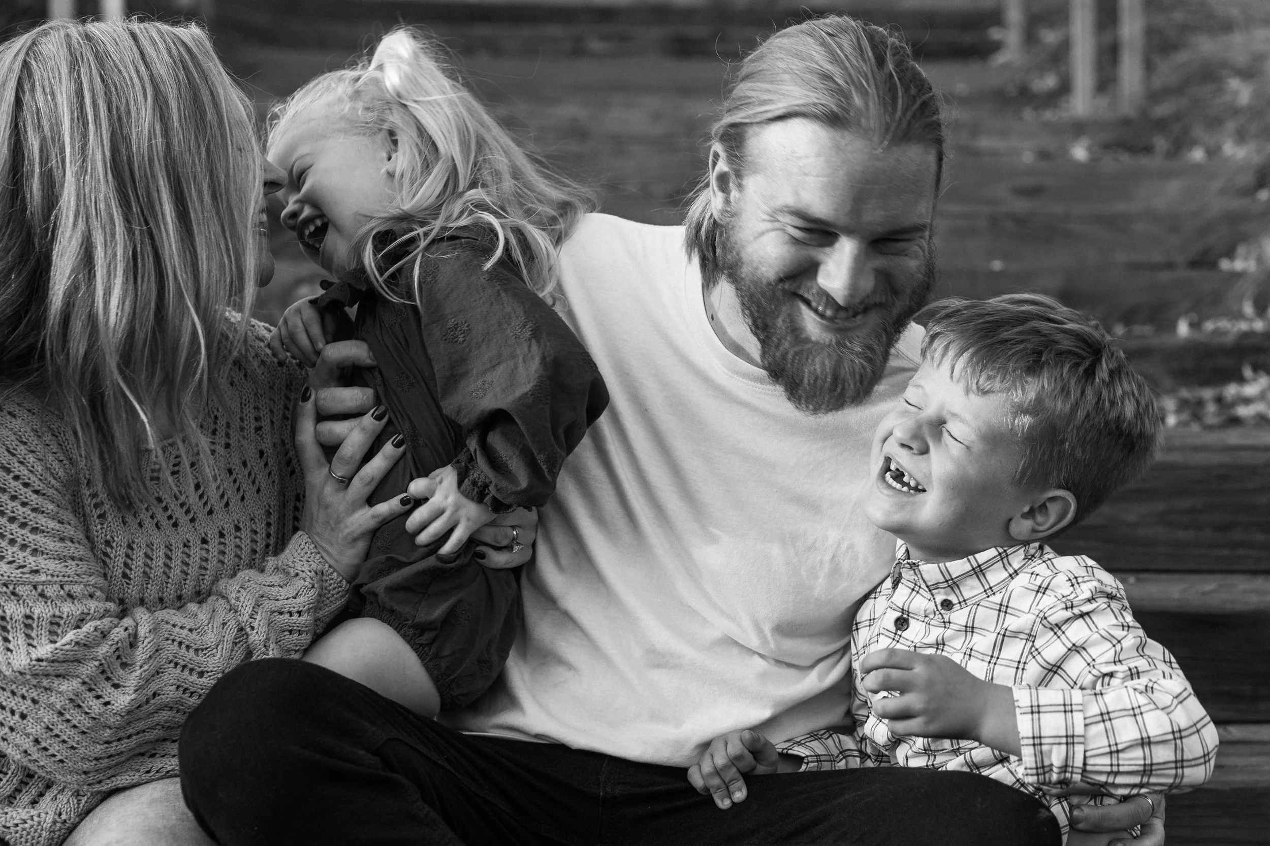 Railroad Park, Downtown Birmingham, AL - A family of four laughing and playing together outdoors, with a woman, man, young boy, and girl.