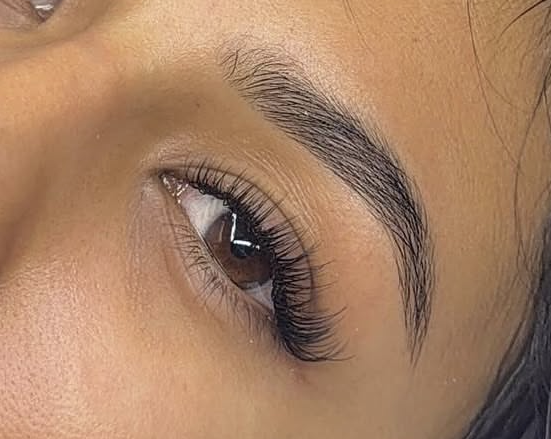 Close-up of a person's eye with well-groomed eyebrow and long eyelashes.