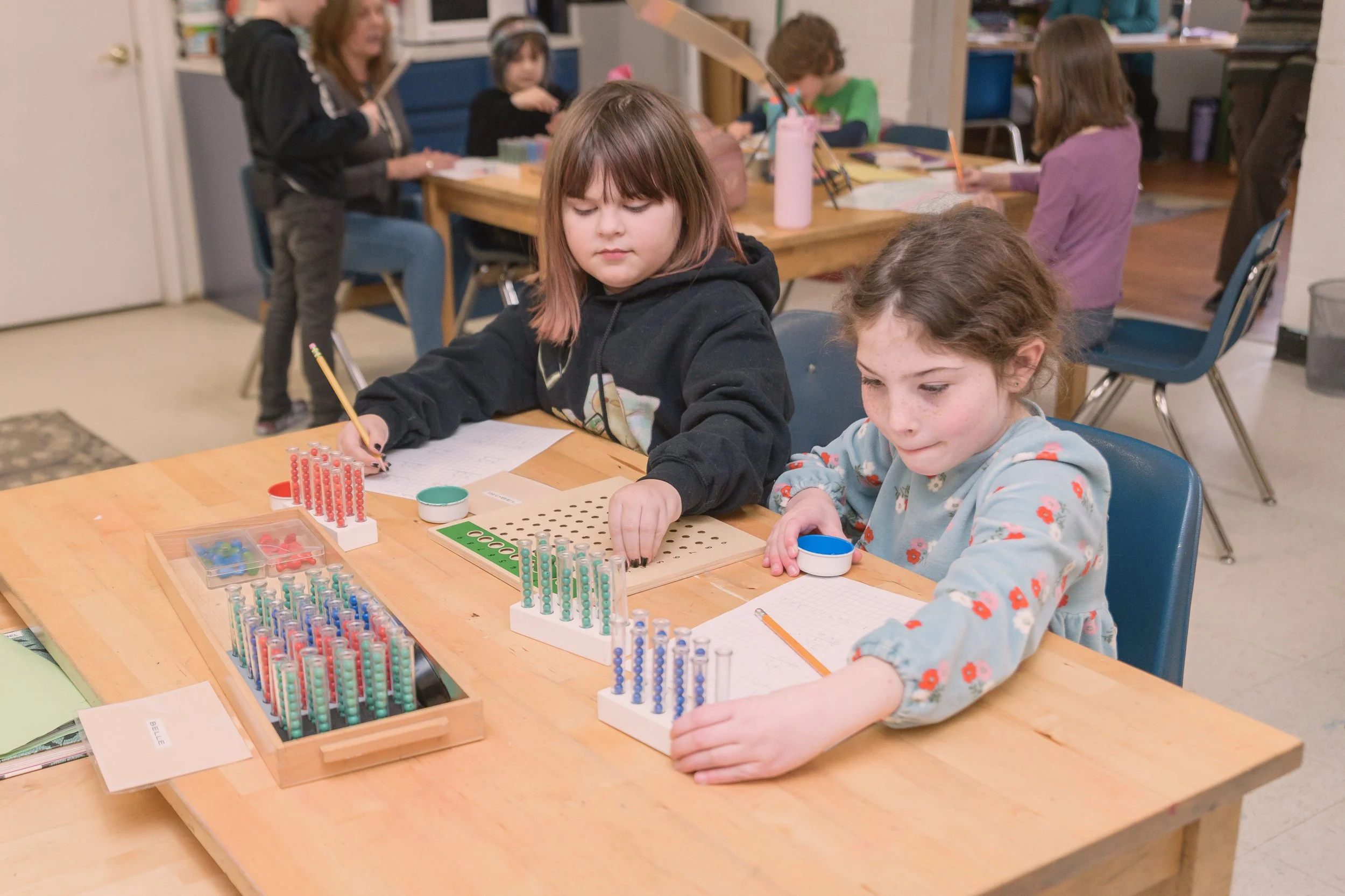 Children playing with abacus at a table in a classroom or activity room.