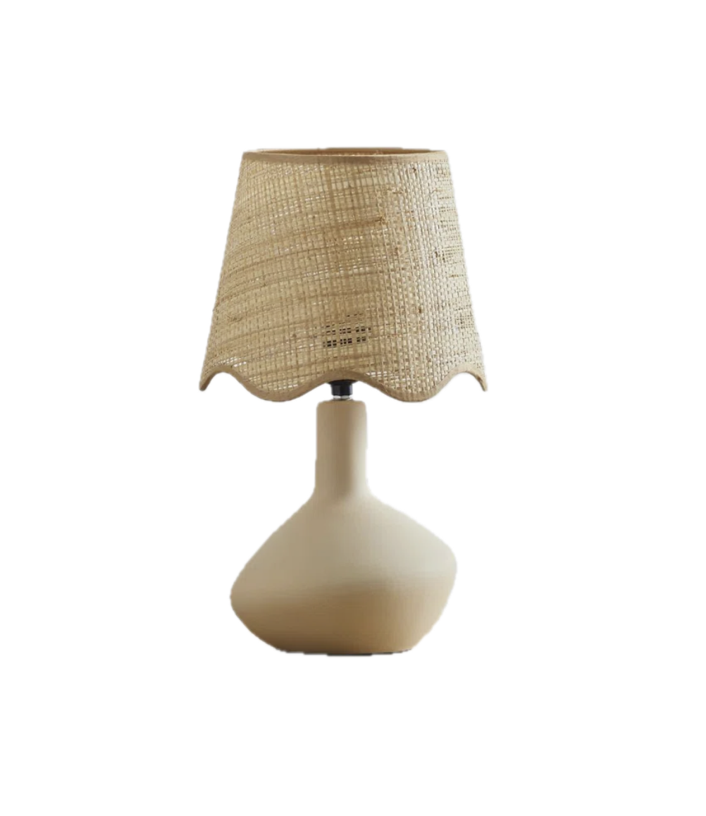 Cream-colored table lamp with a textured beige fabric lampshade on a black background.