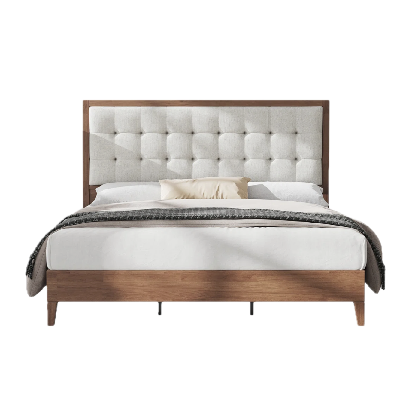 Modern bed with a padded, tufted beige headboard, white bedding, cream pillow, and dark patterned throw blanket.