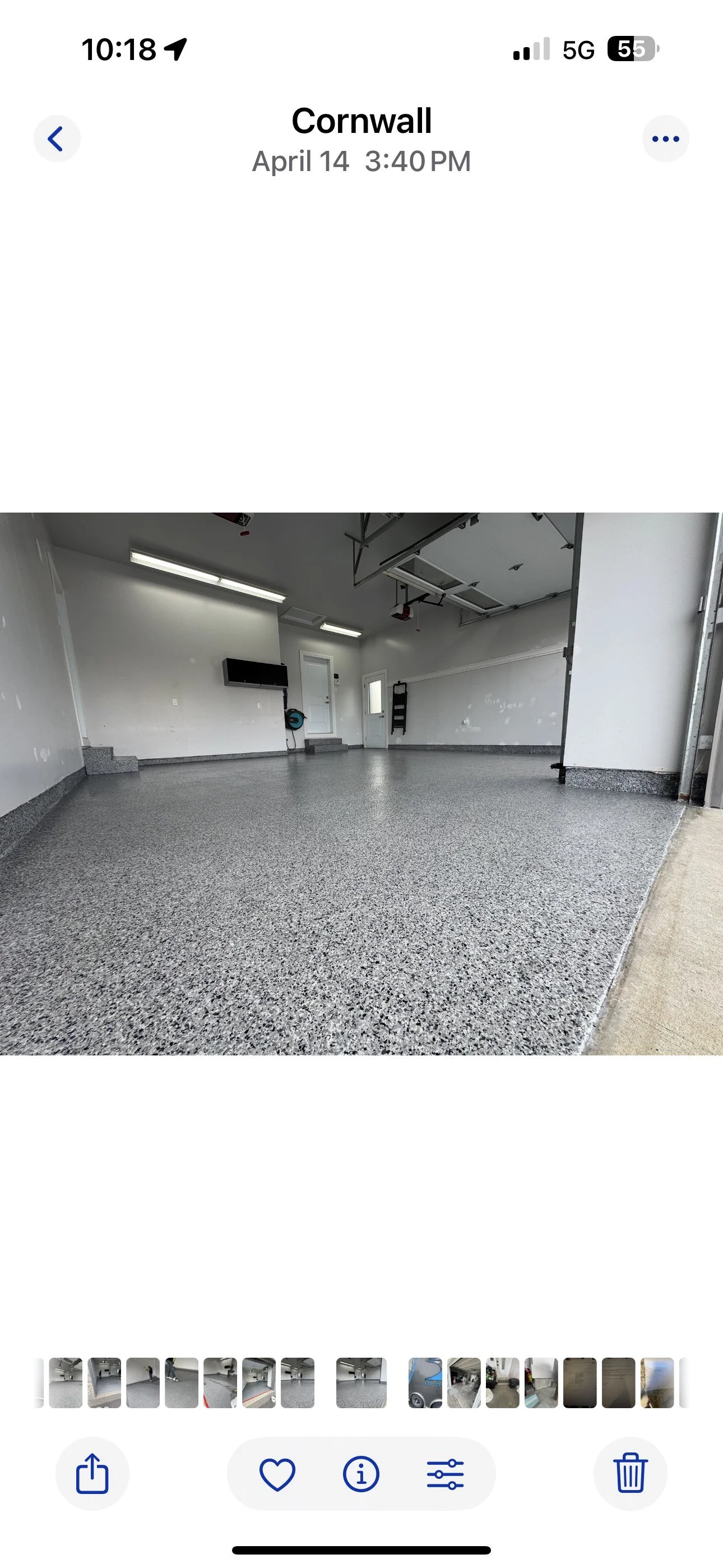 Empty residential garage with polished concrete floor, white walls, ceiling-mounted garage door opener, heater, and storage ladder.