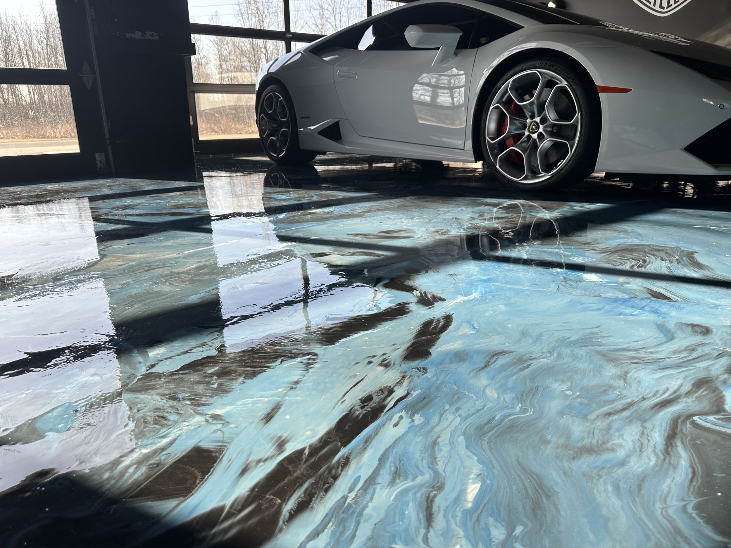 A white luxury sports car parked indoors on a marble floor, with large windows in the background.