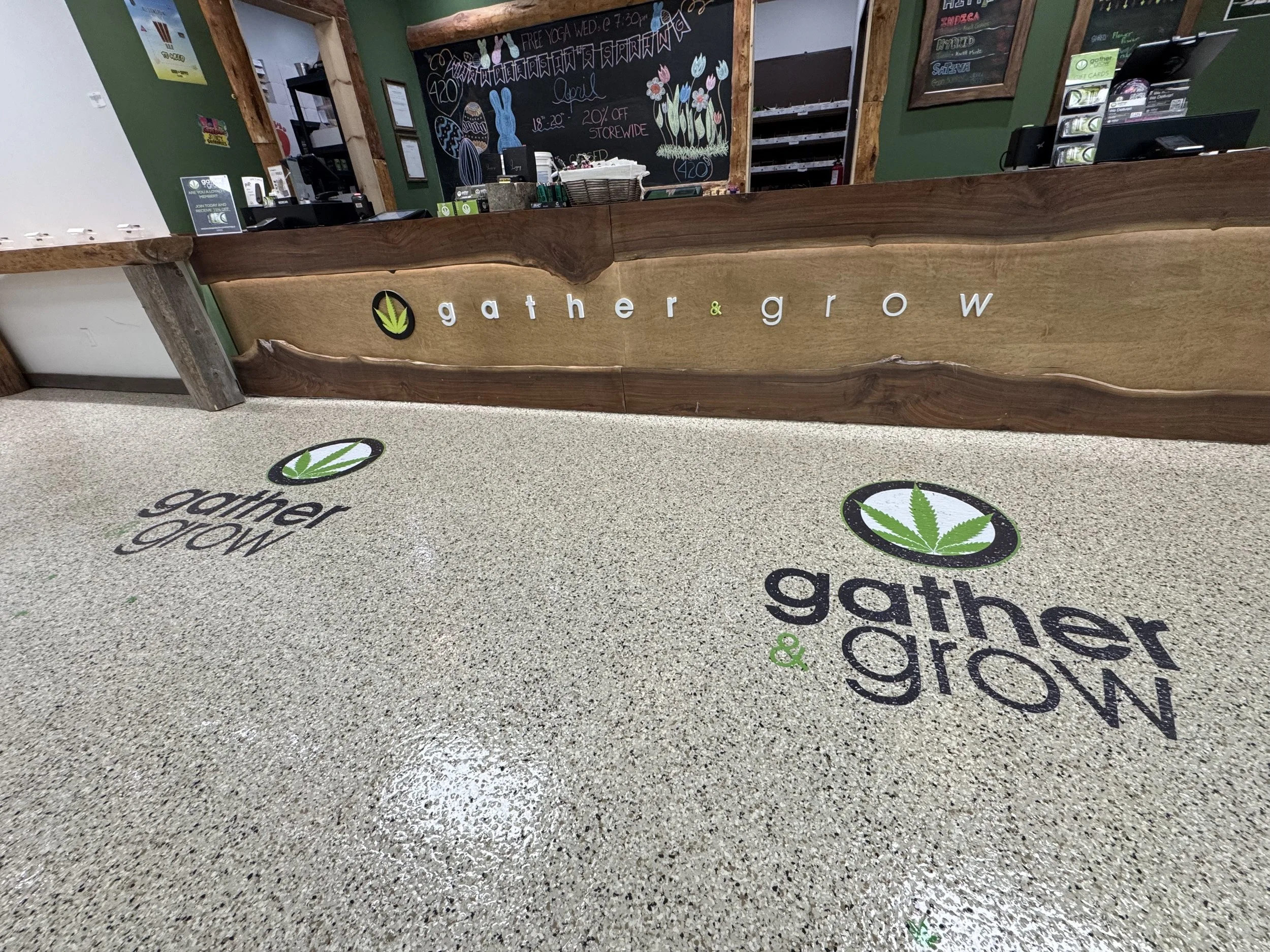 Floor mat and reception desk with logo and text 'gather & grow' at a cannabis store.