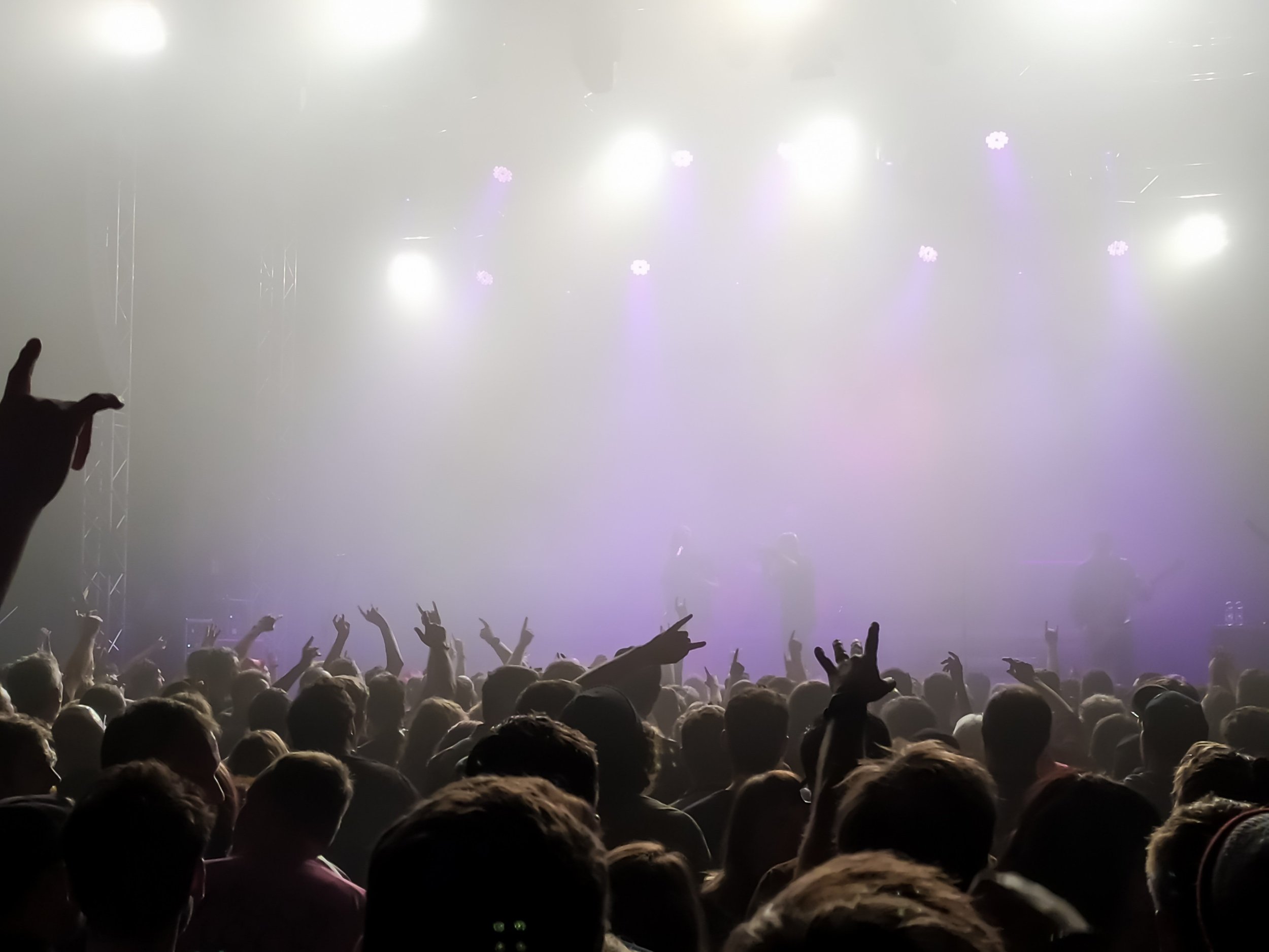 Escenario de concierto con luces y una gran multitud de personas disfrutando y bailando.