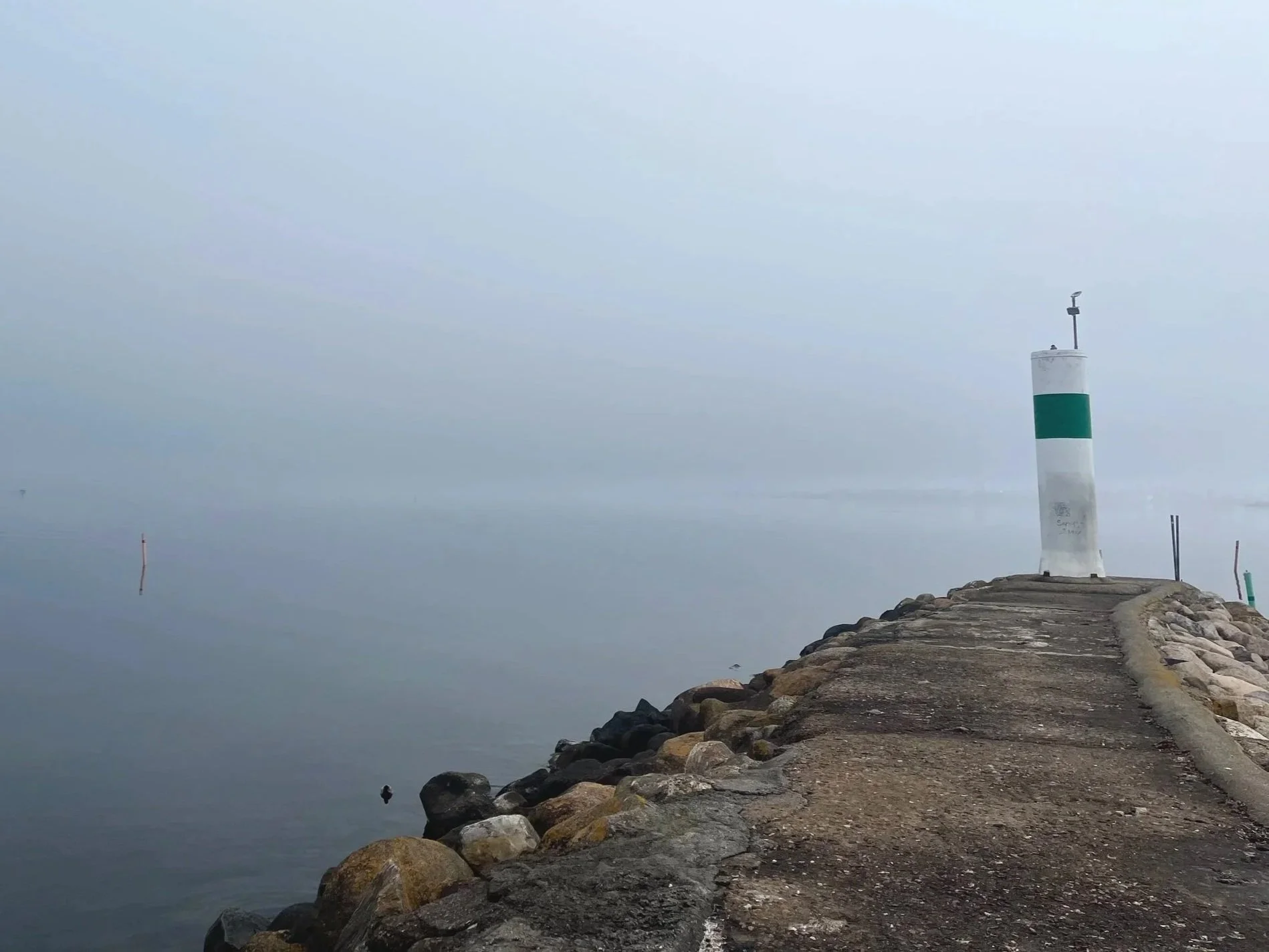 Stenpir med fyr vid strand, relevant för vattenverksamhet och tillstånd