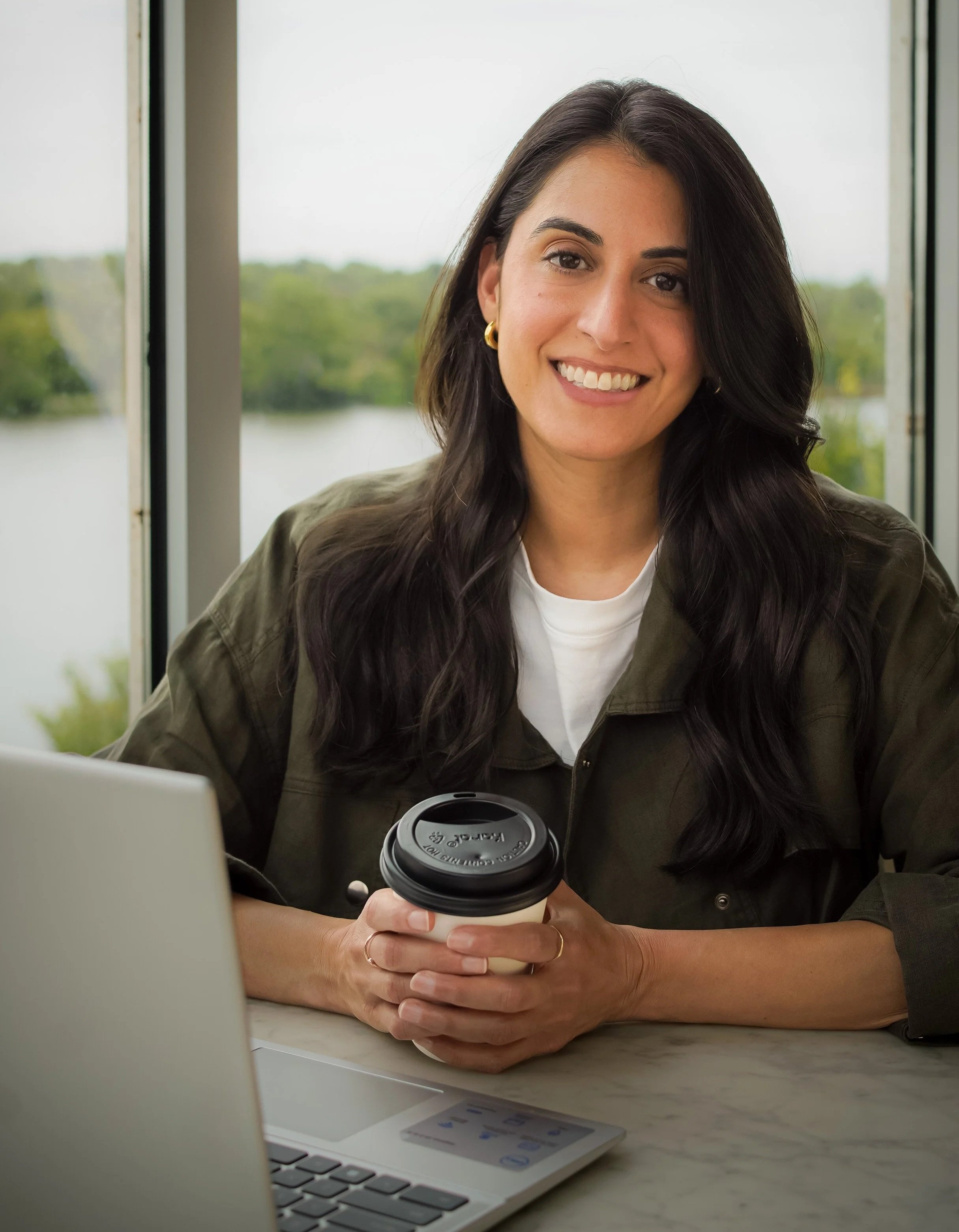 Amrita Singh, career & leadership coach, smiling at the camera with a coffee cup in her hand