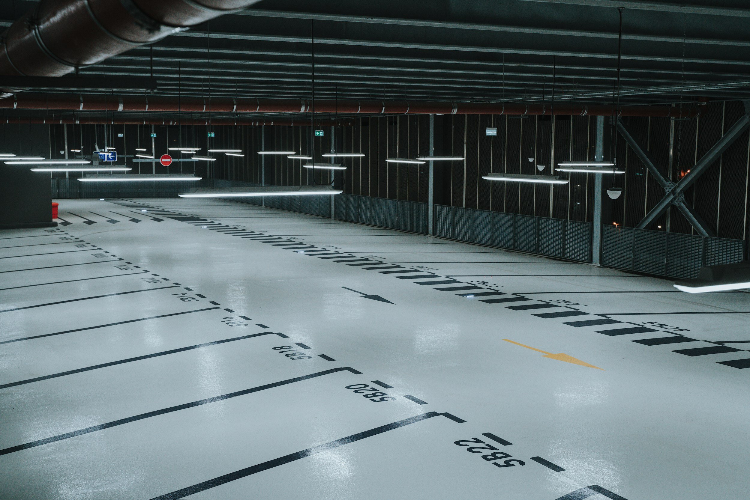 Empty indoor parking garage with numbered parking spaces and overhead lighting.