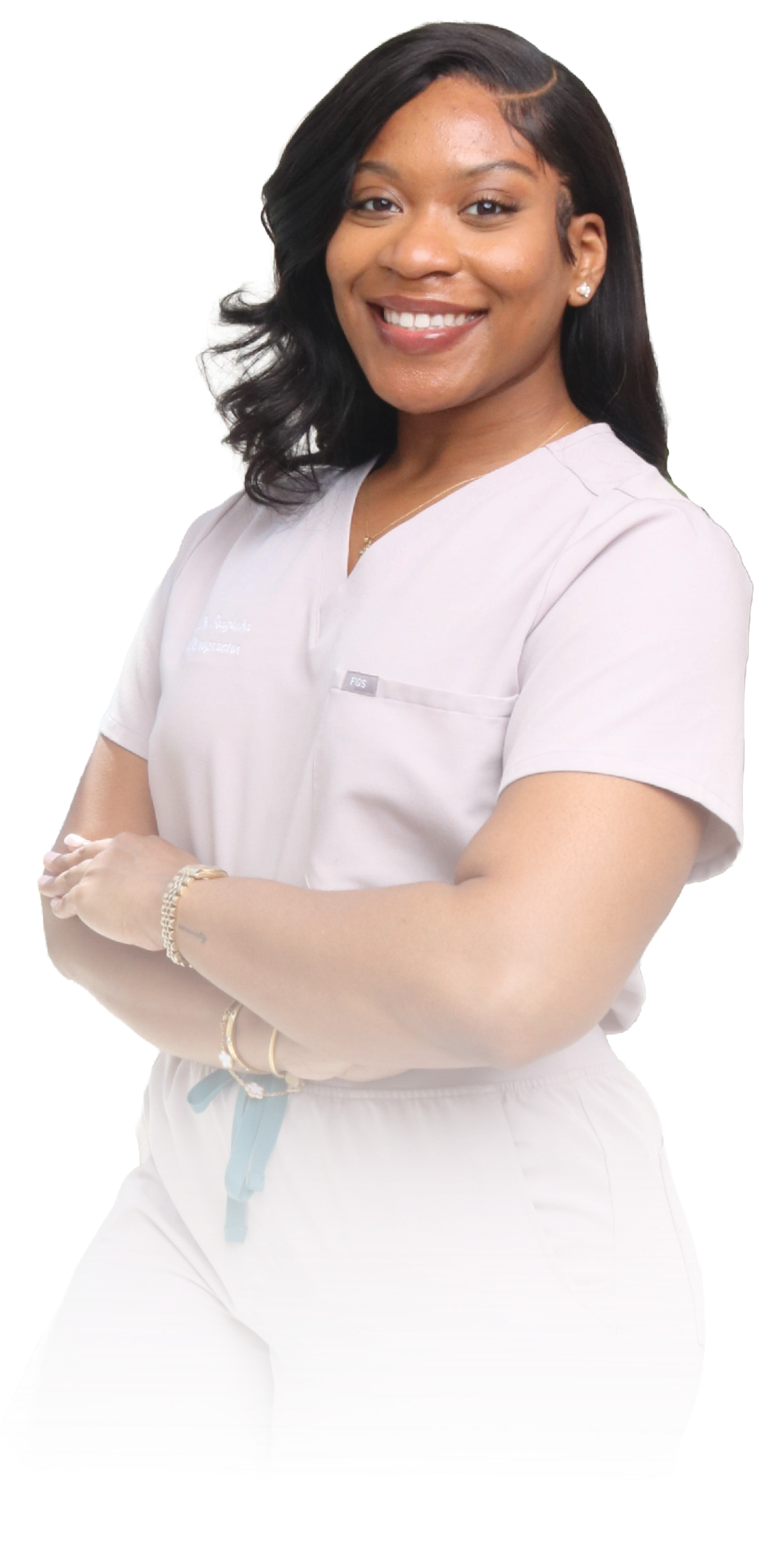 Portrait of a smiling female healthcare professional with dark hair, wearing light-colored scrubs, standing with arms crossed.