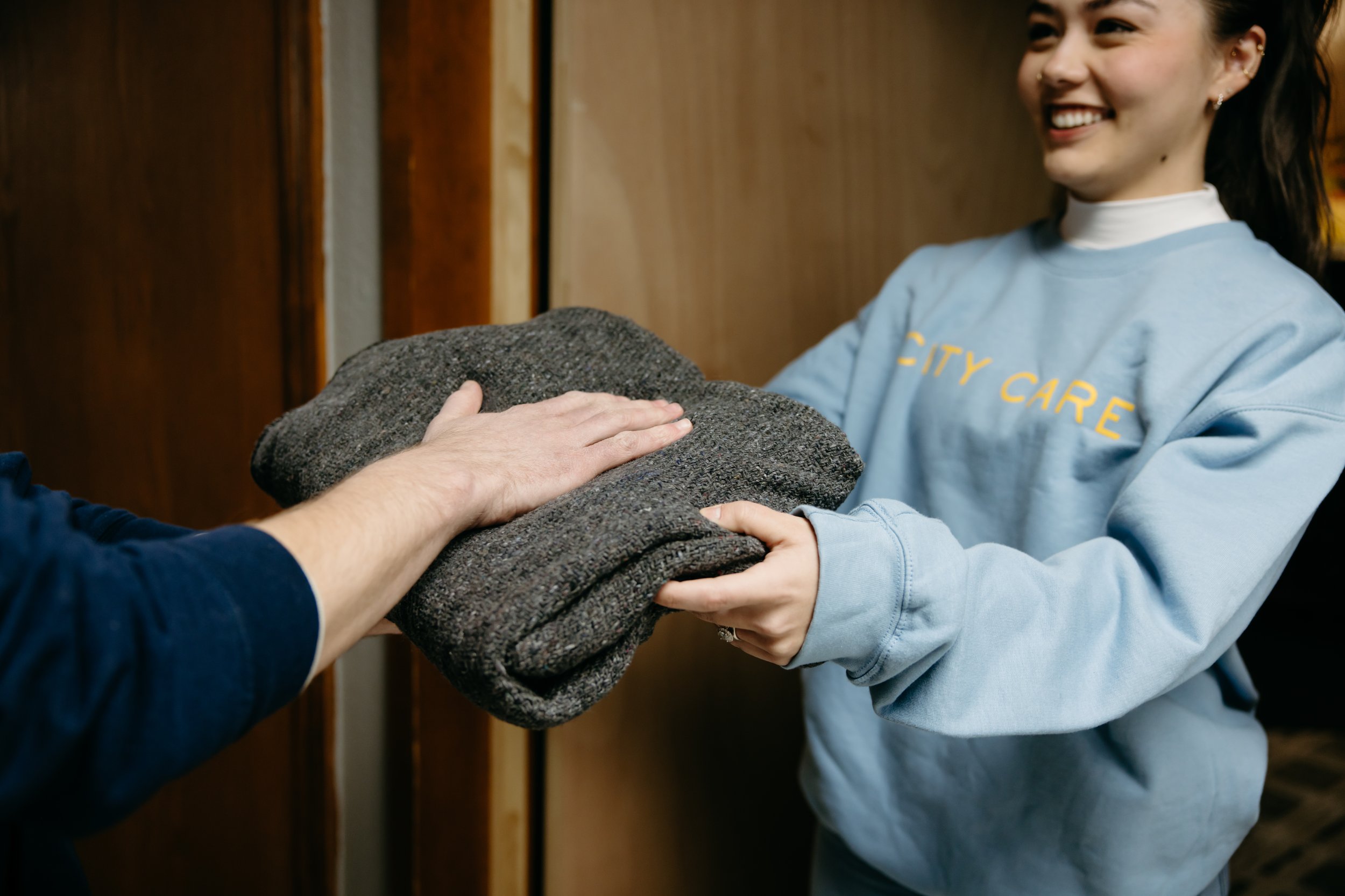 a woman kindly hands a blanket to someone