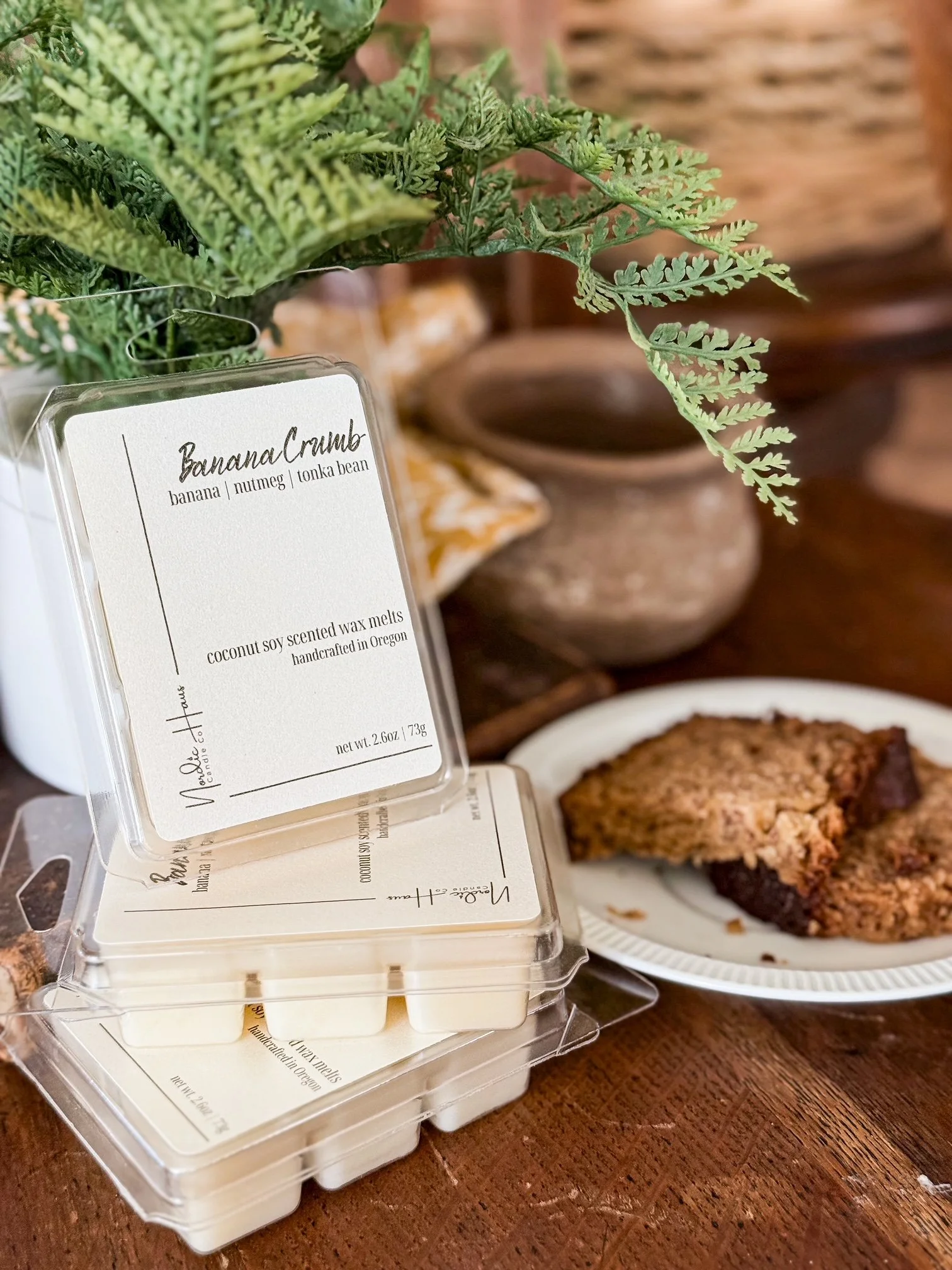 Banana Crumb scented wax melts are displayed next to a slice of banana bread.