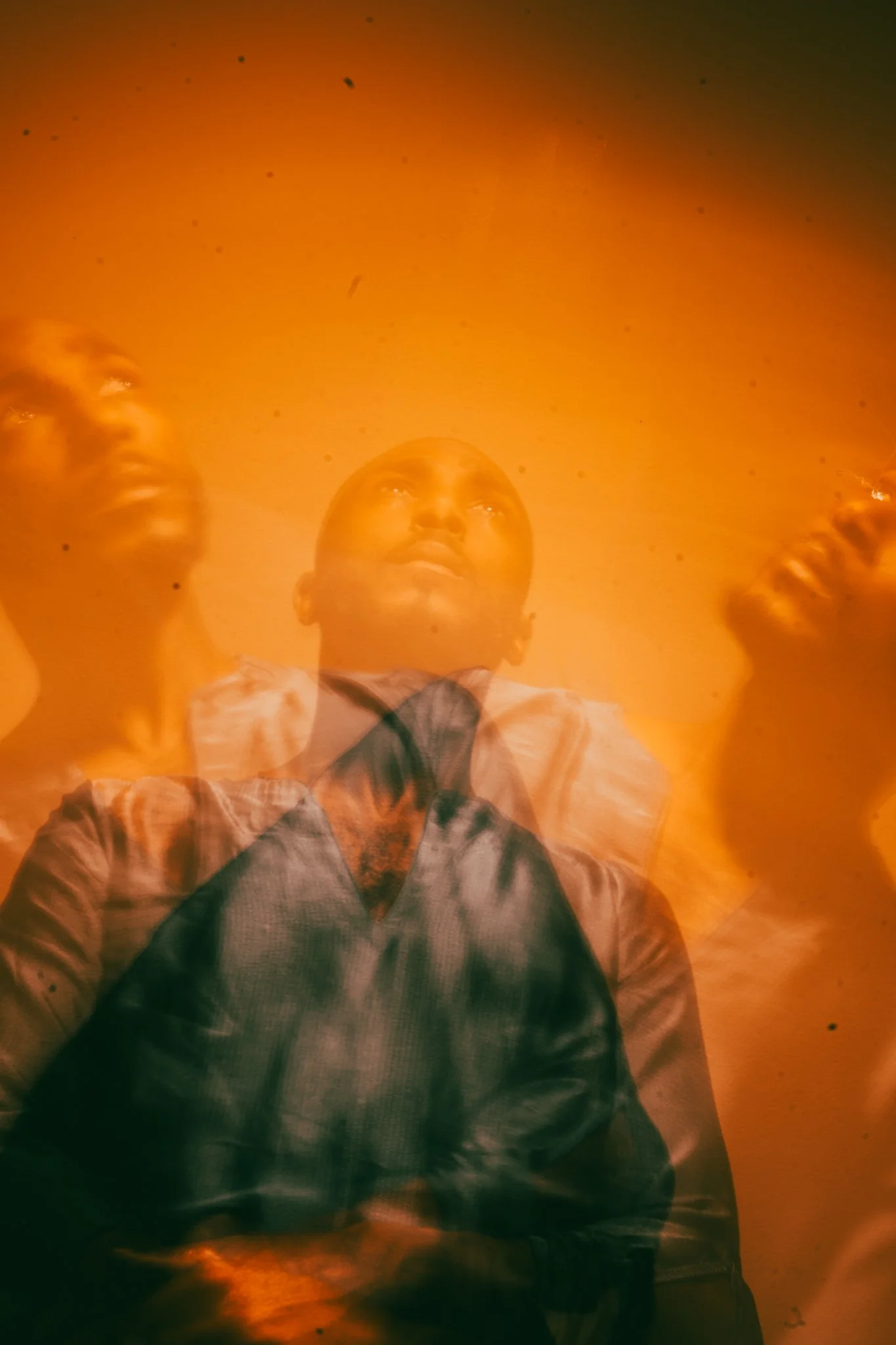 Three people look up as flames and smoke billow into the sky, with orange and yellow light illuminating the scene.