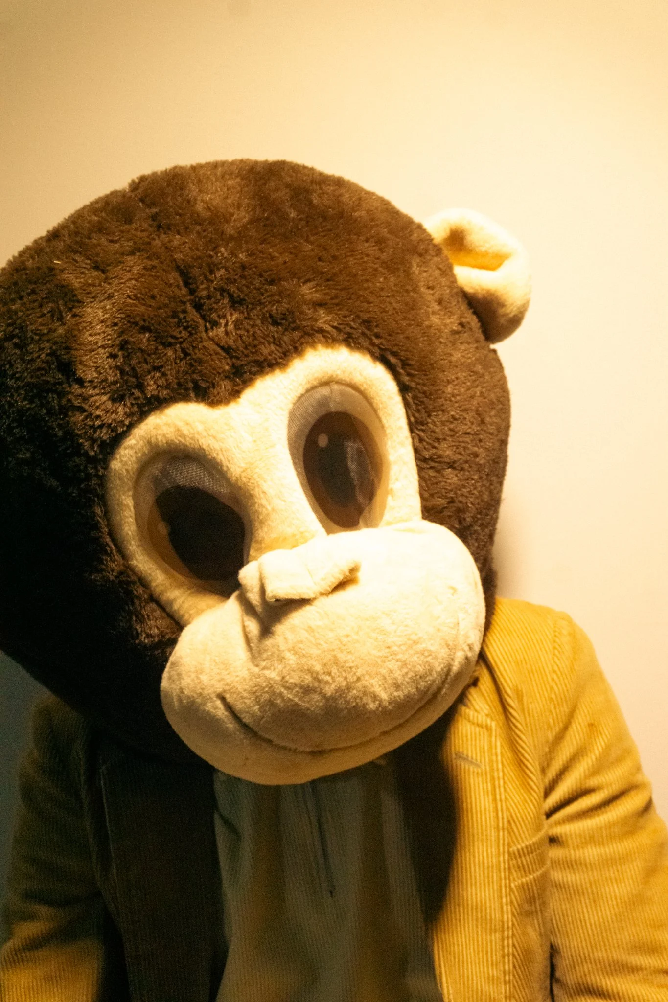 Person in a bear costume taking a selfie, wearing a striped shirt and a yellow jacket.