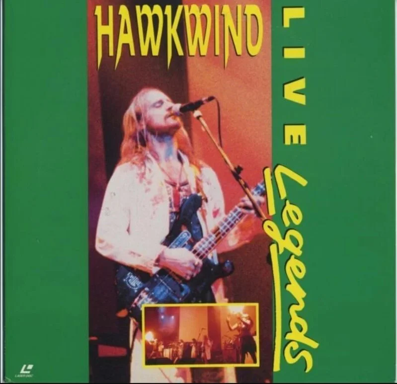 Album cover featuring a female musician singing into a microphone while playing an electric guitar. The background includes smaller images of a band performing on stage. The text on the cover reads "Hawkwind - Space Ritual" in bright yellow and green letters.