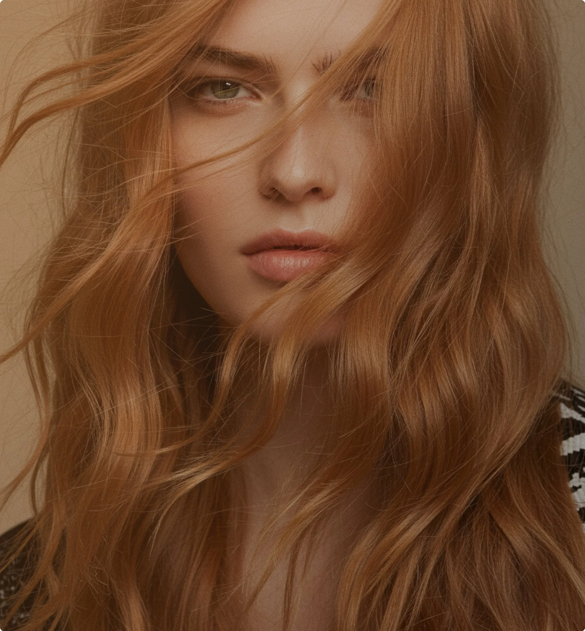 Close-up of a woman with long, wavy red hair partially covering her face. She has light-colored eyes, full lips, and light skin.