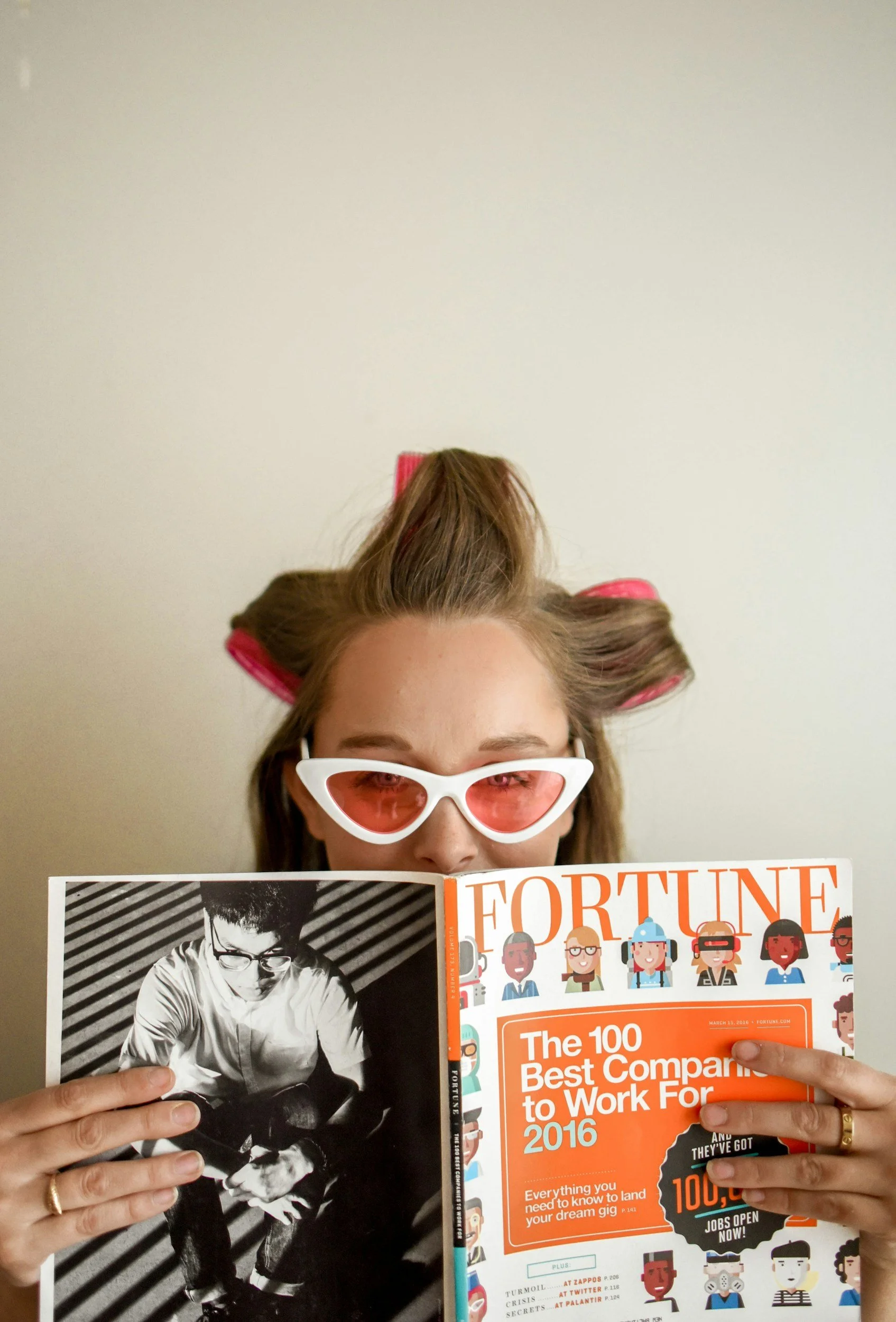 A person with hair rollers, wearing white sunglasses, holding a magazine titled 'Fortune,' partially covering their face.