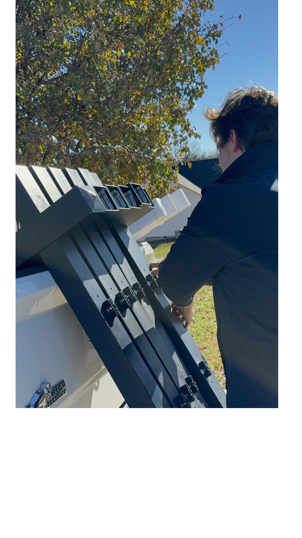 A person wearing a black jacket with real estate sign posts in Charlotte, NC with trees and a house in the background.