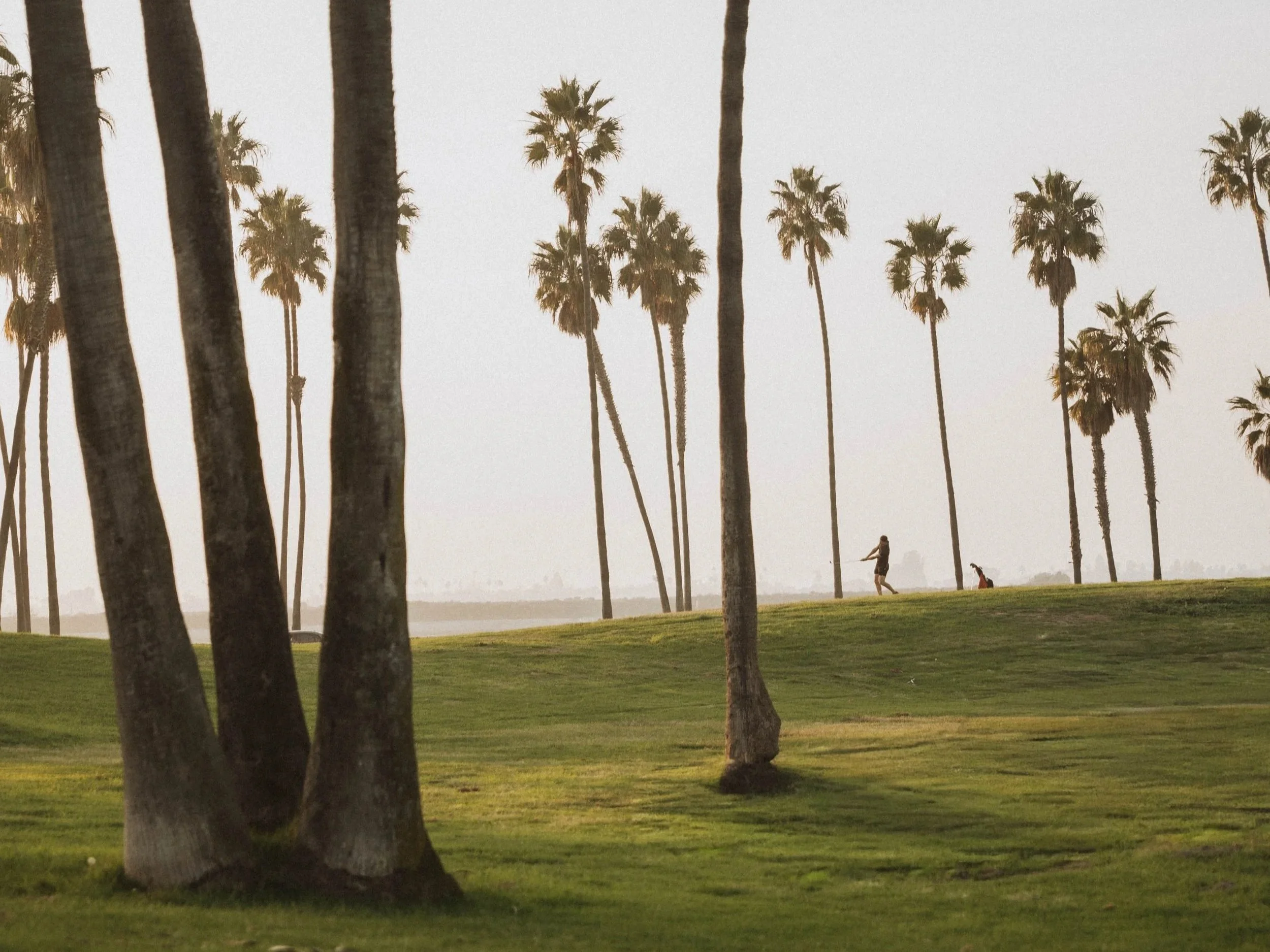 golfer practicing wedge shot at sunset