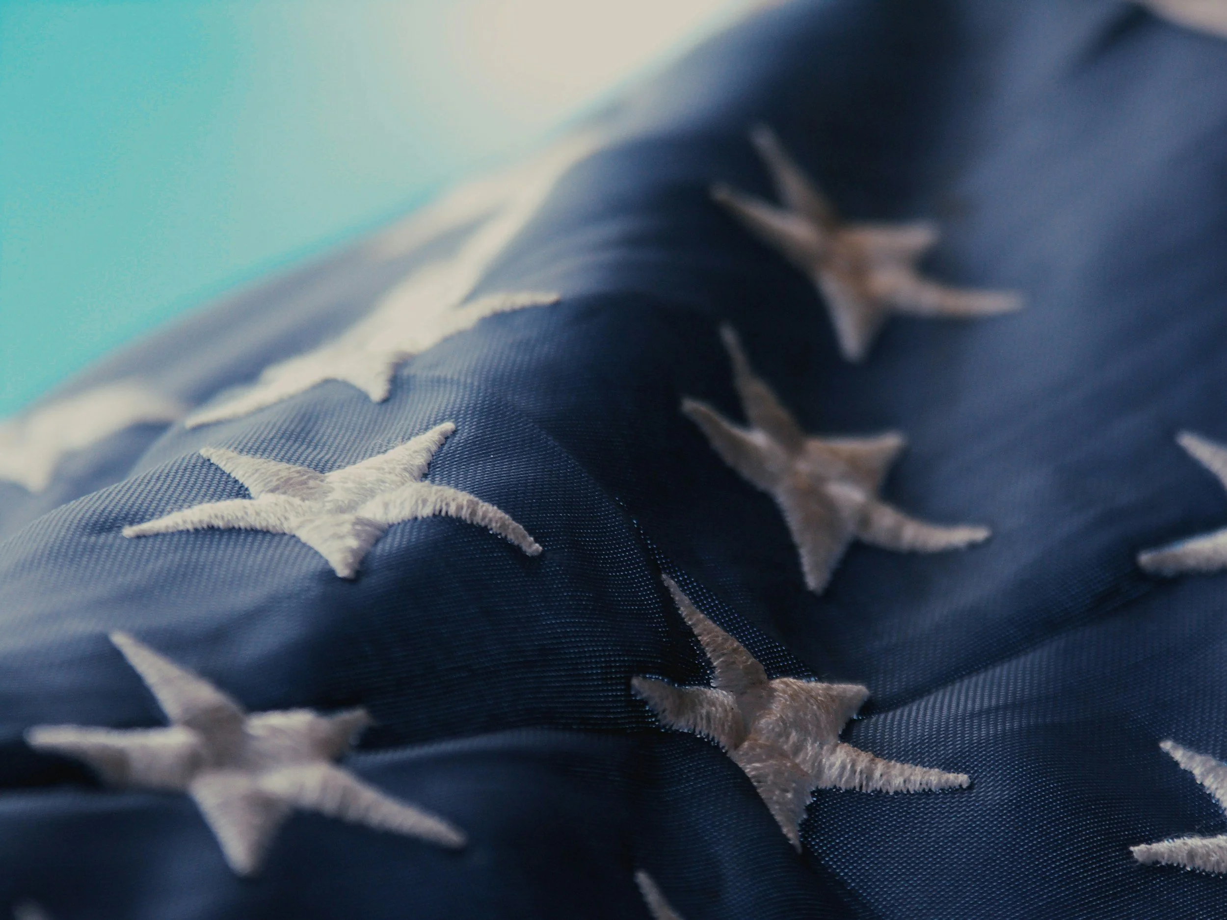 Close-up of a section of blue denim fabric with white star-shaped embroidery.