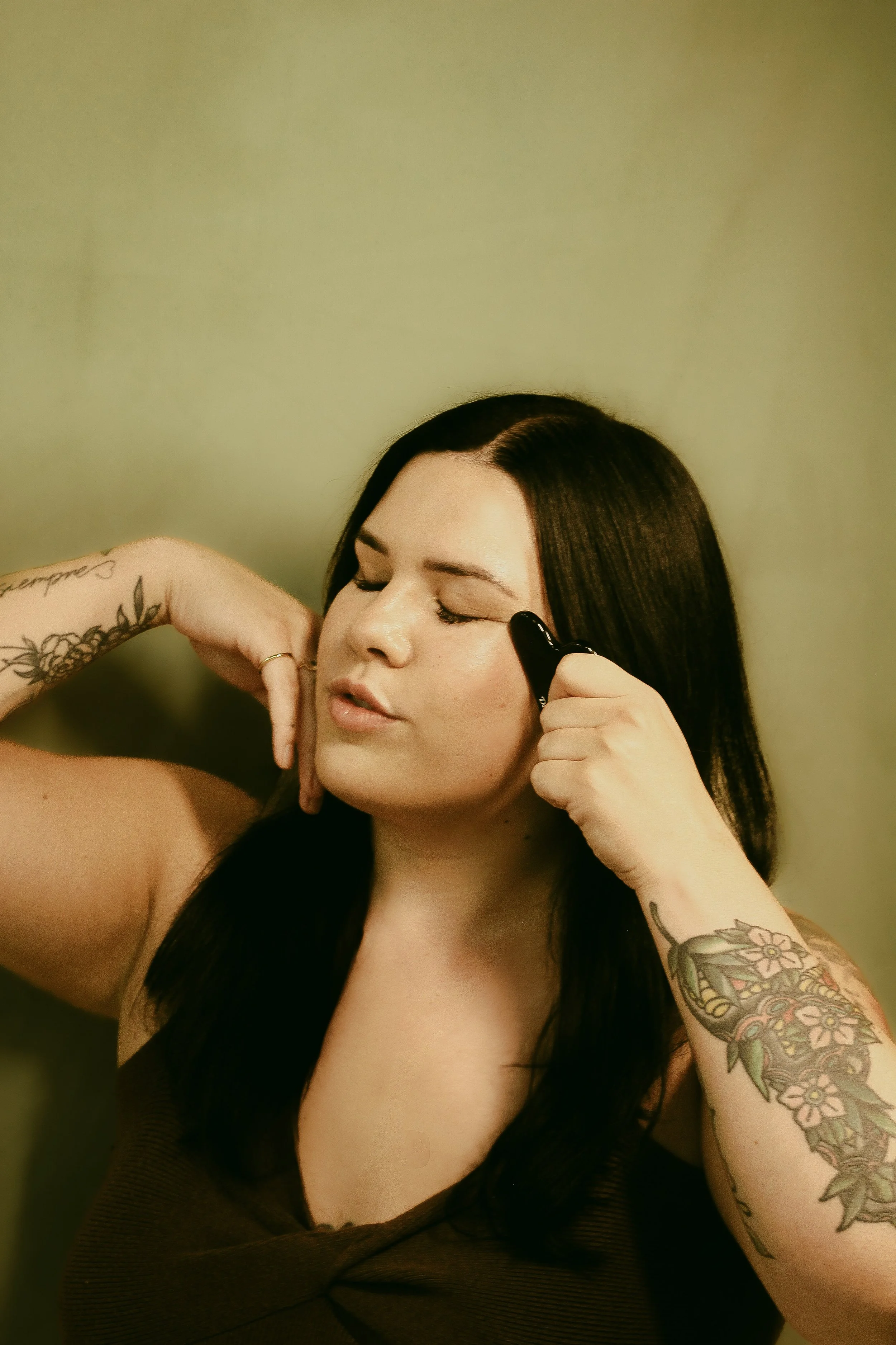 Sam Zbikowski, Founded and Advanced Esthetician at Dahlia Beauty Bar holding a gua sha facial massage stone
