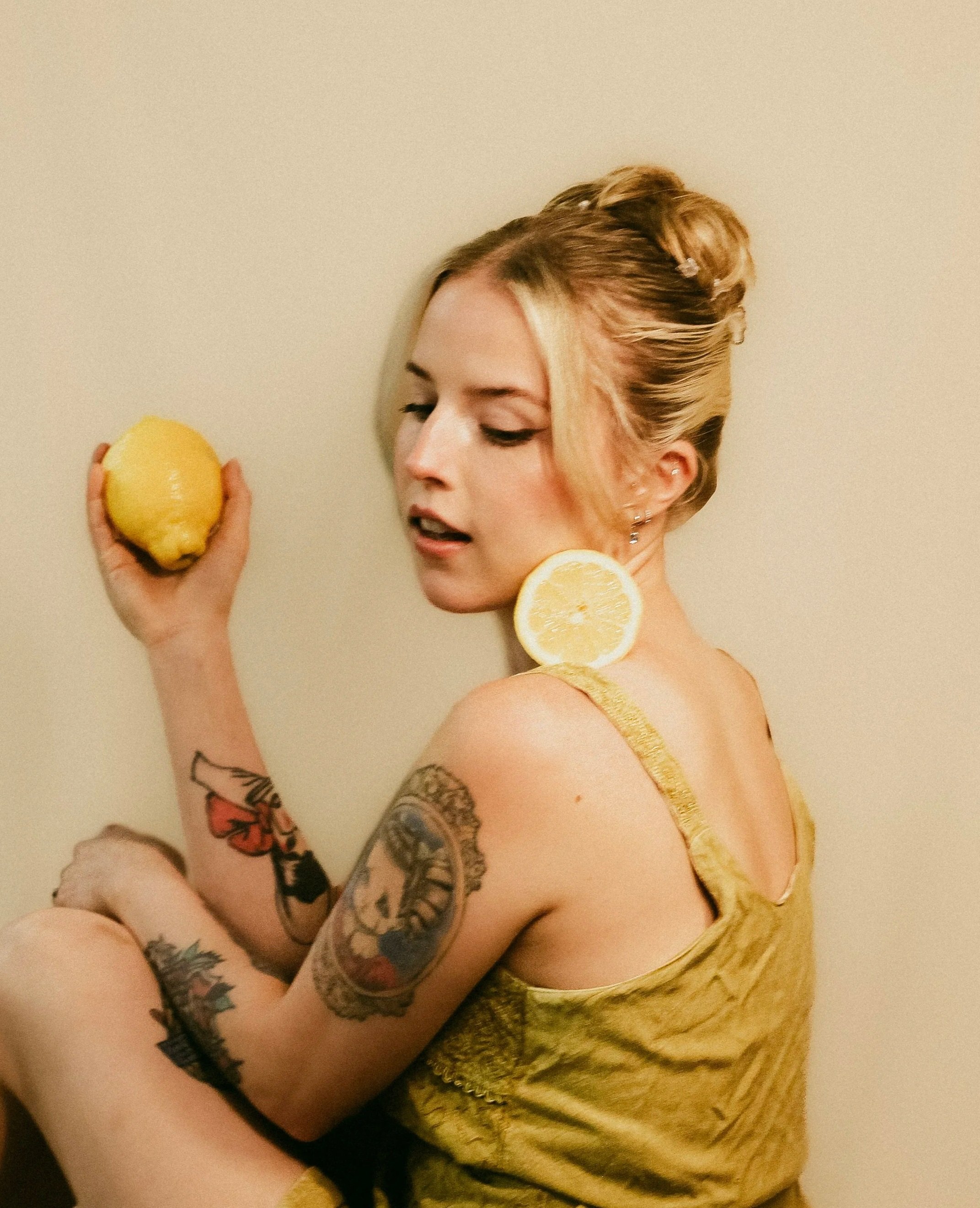 Emma Salazar, Advanced Esthetician at Dahlia Beauty Bar (best day spa in Toledo, Whitehouse, Waterville, Perrysburg, Maumee) holding lemons as plant-based skincare and wellness are a big focus at Dahlia Beauty Bar.