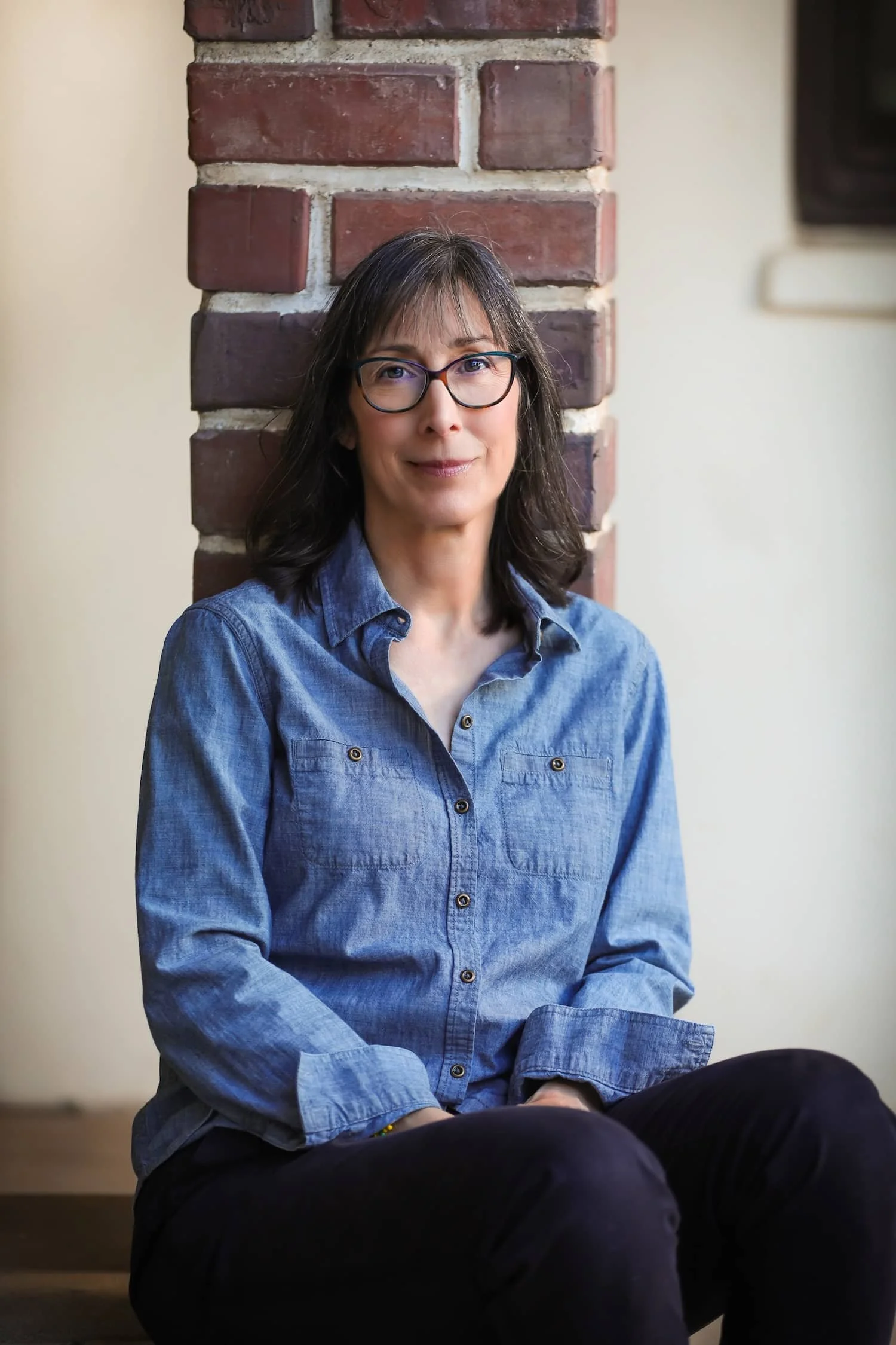 Jean Grabow, sitting against a brick post