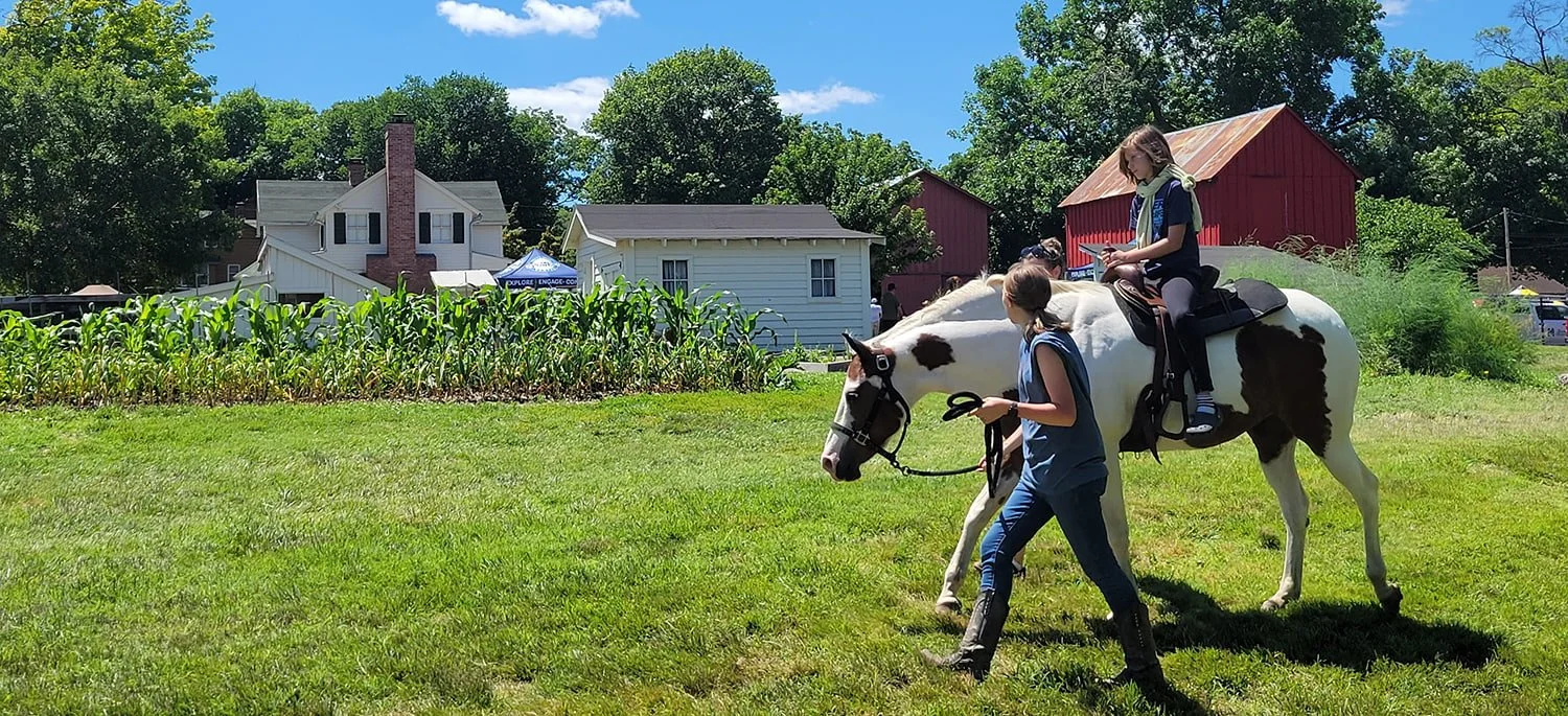 a woman leads a horse a girl is riding