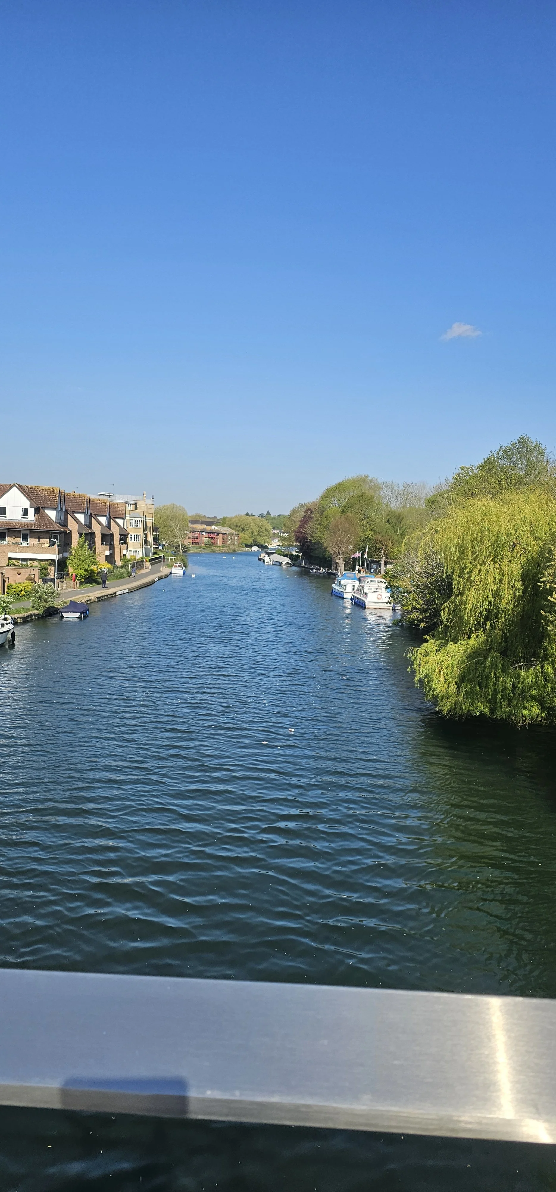 A canal with houses and boats on the sides under a blue sky with some clouds.
