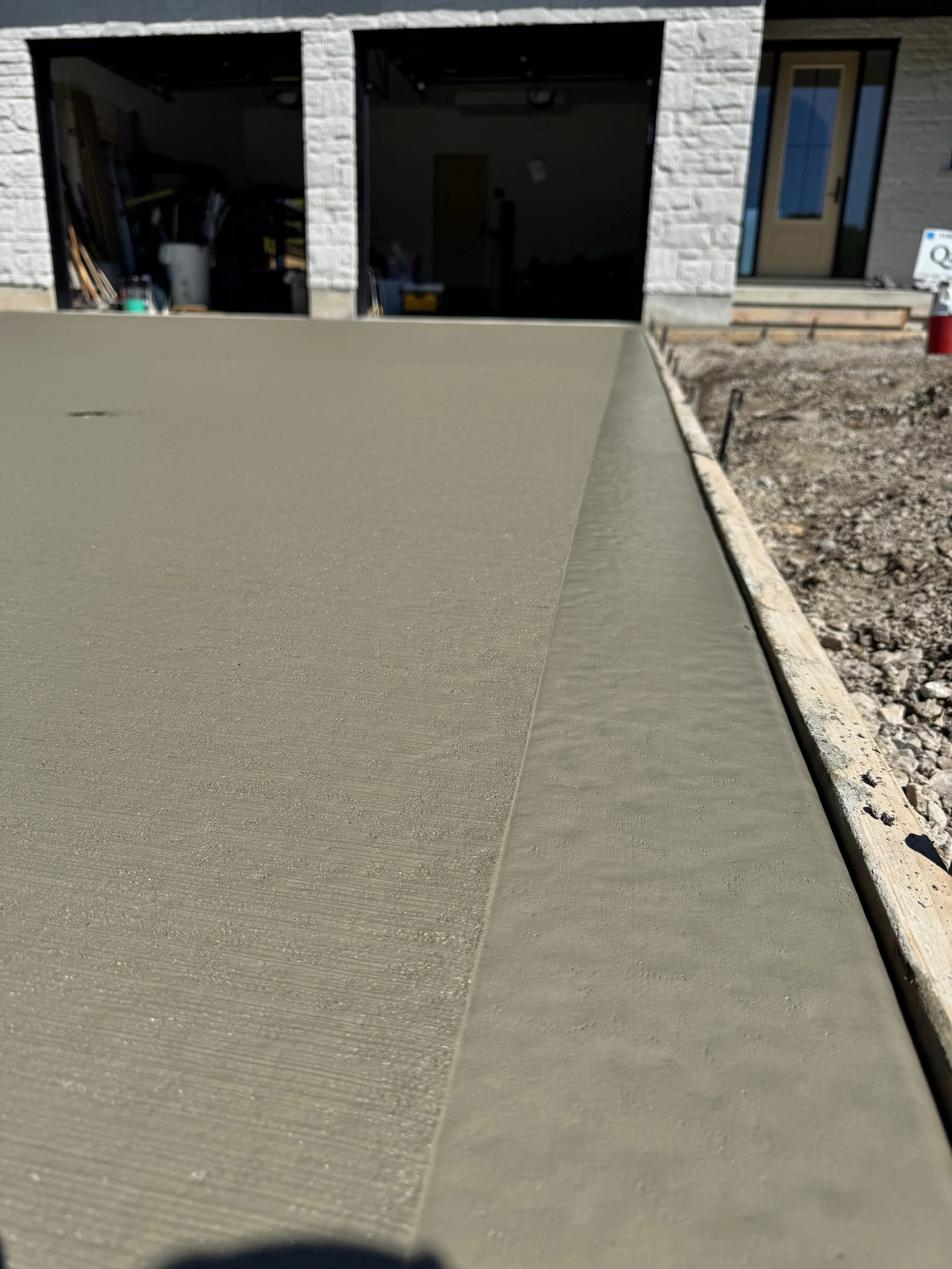 Close-up view of freshly poured concrete slab in front of a house