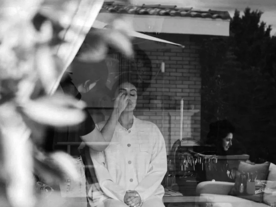 Bridal hair and makeup artist preparing a client in a relaxed, natural setting before a wedding event