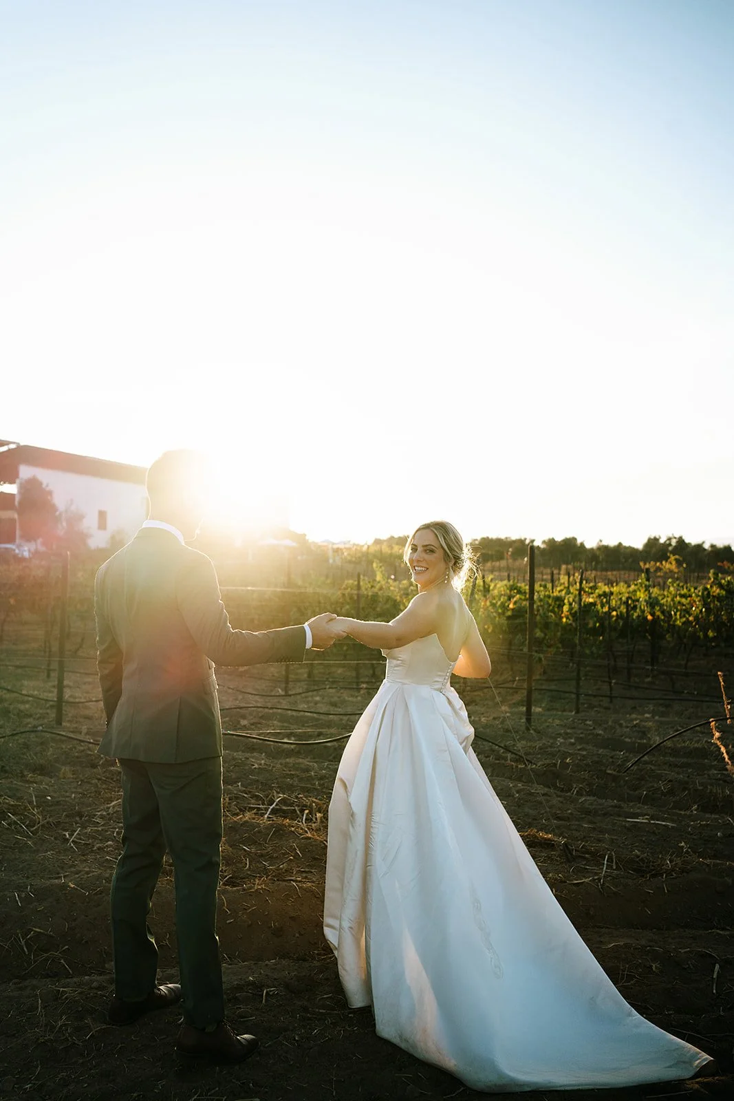 Bride with flawless, natural glam makeup holding hands with her partner at sunset, glowing with confidence and timeless bridal beauty