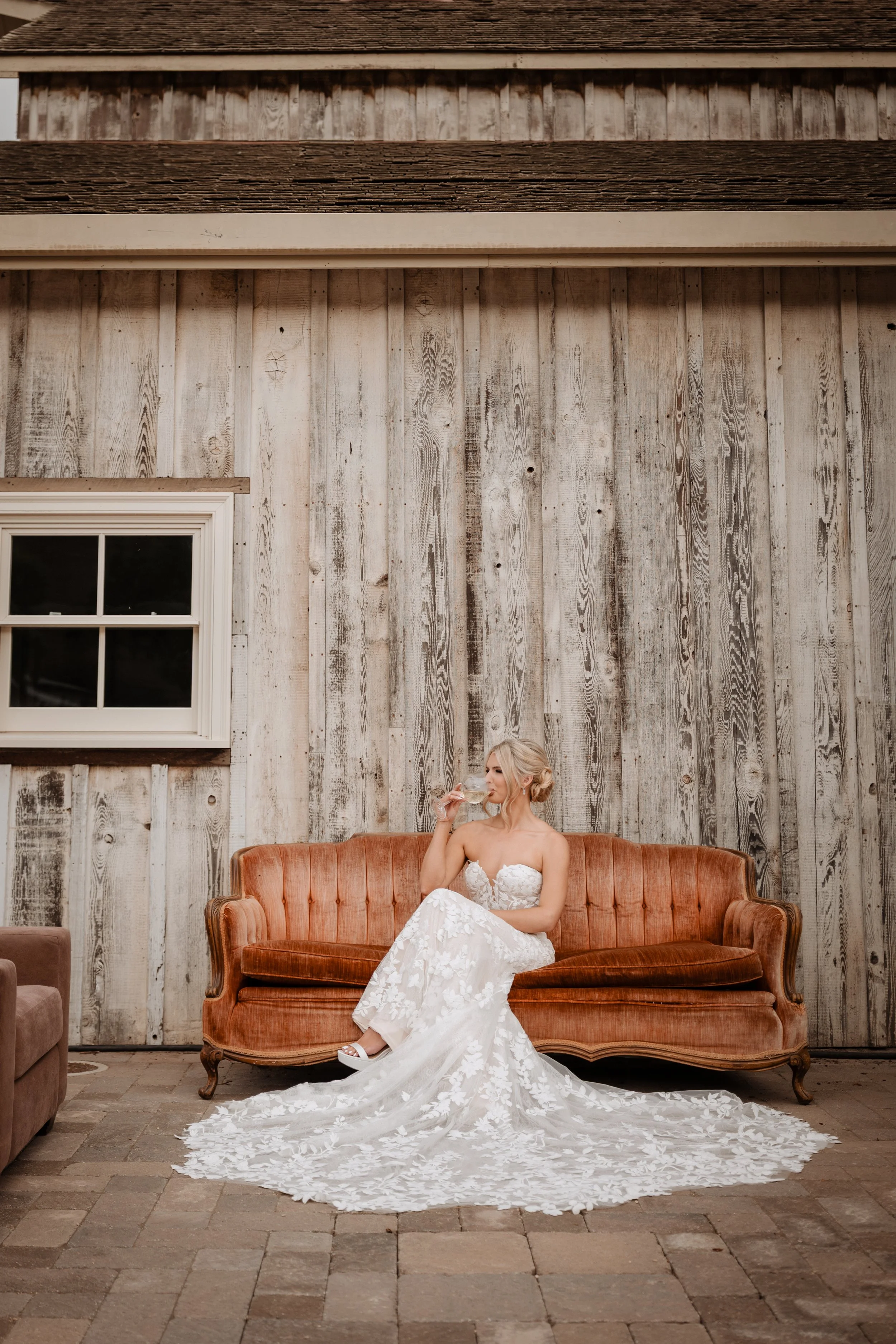 Bride with soft, natural glam makeup relaxing on a vintage sofa, looking calm, confident, and effortlessly beautiful before her wedding