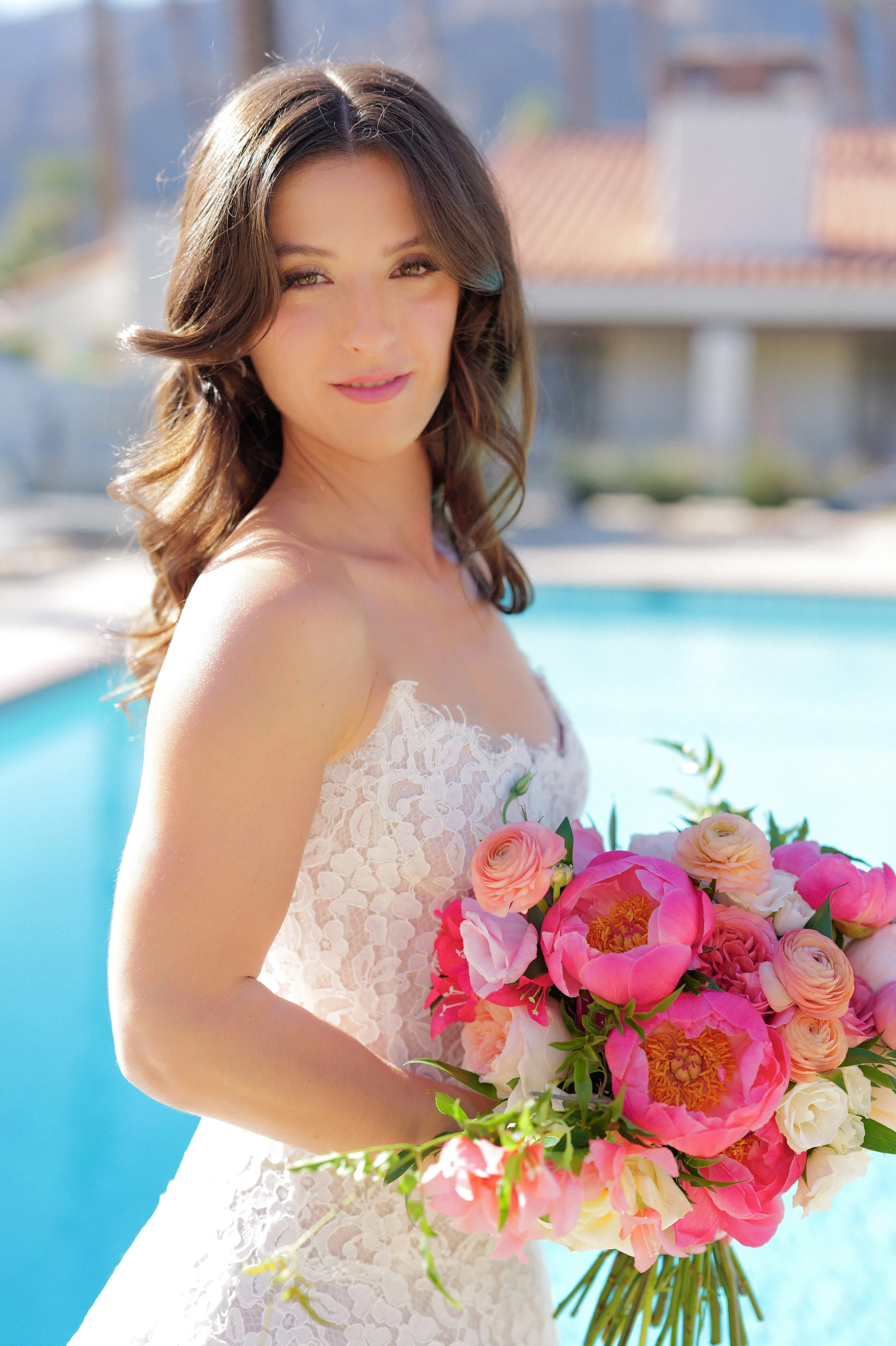 Bride with glowing, natural bridal makeup and styled waves holding her bouquet, looking confident and camera-ready