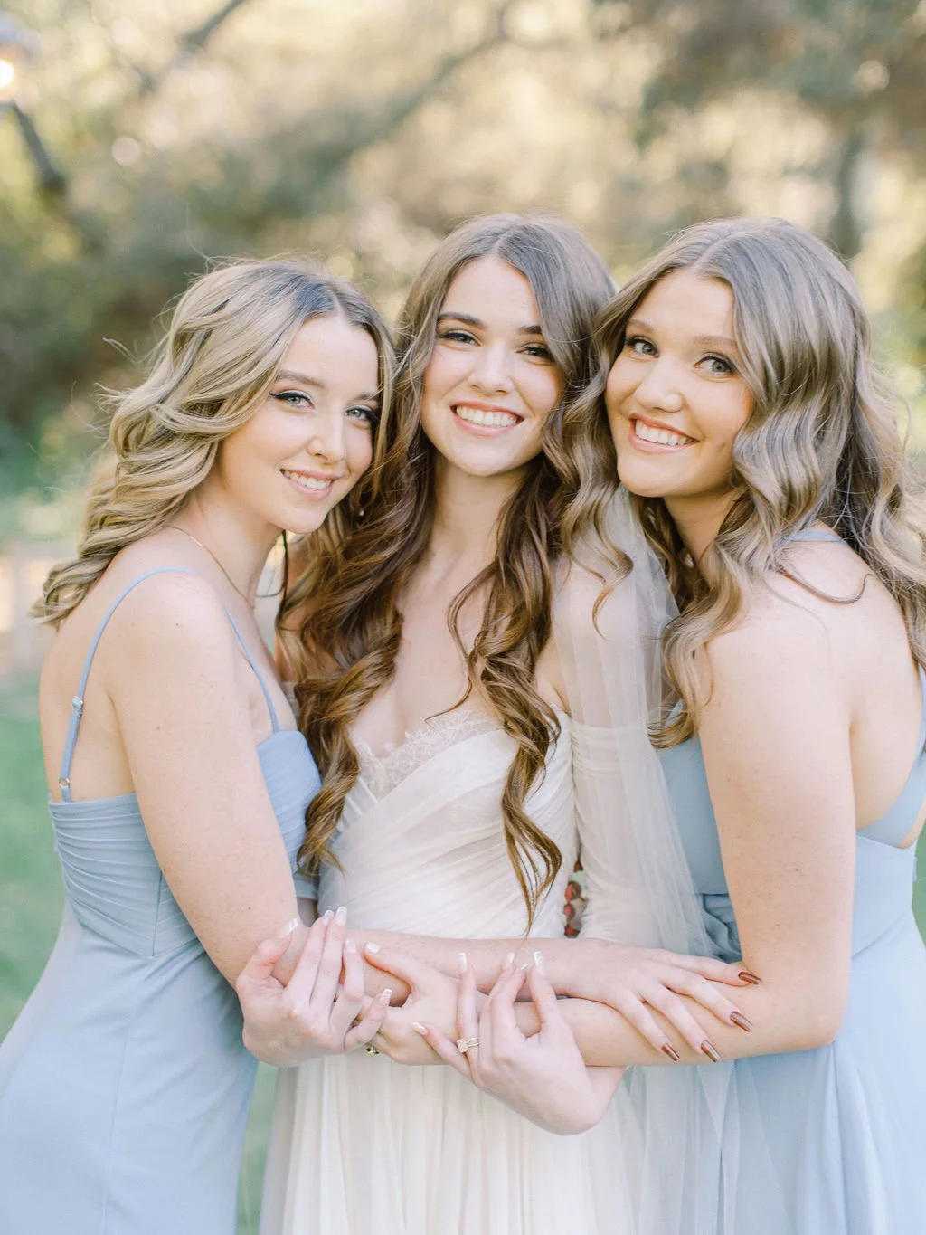 Bridal party with cohesive, soft glam hair and makeup sharing a joyful moment together before the ceremony